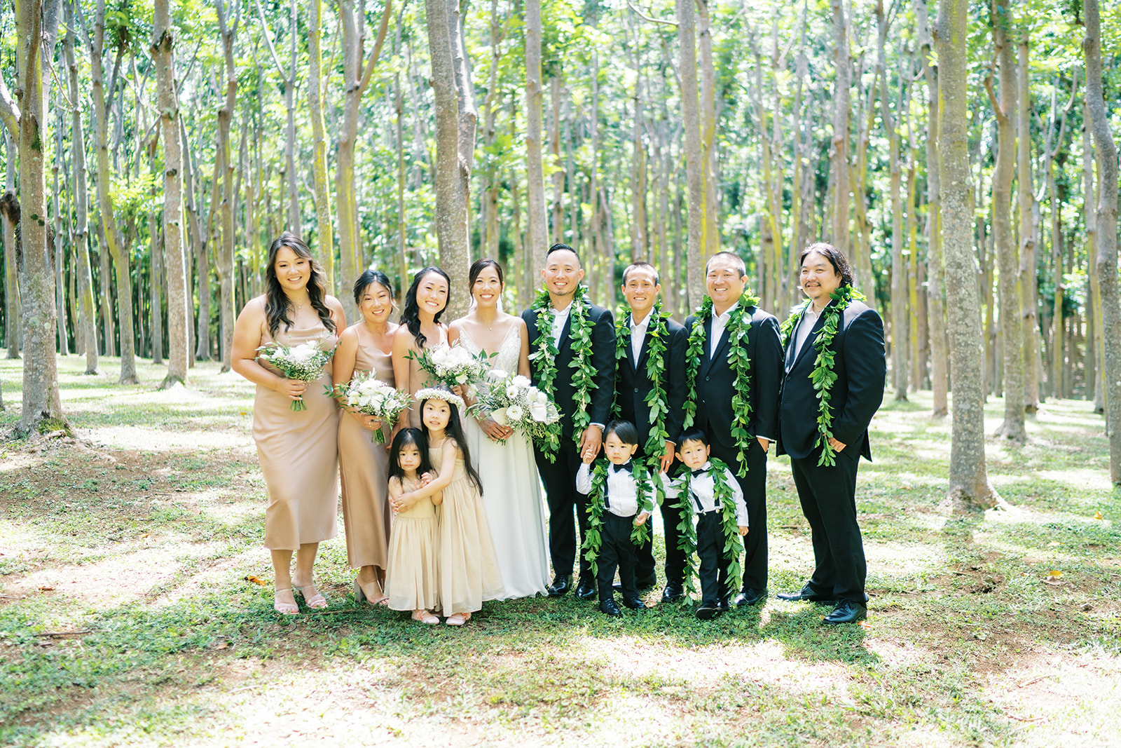 A family dressed in formal attire posing for a group photo during Wedding at Na ‘Āina Kai Botanical Gardens
