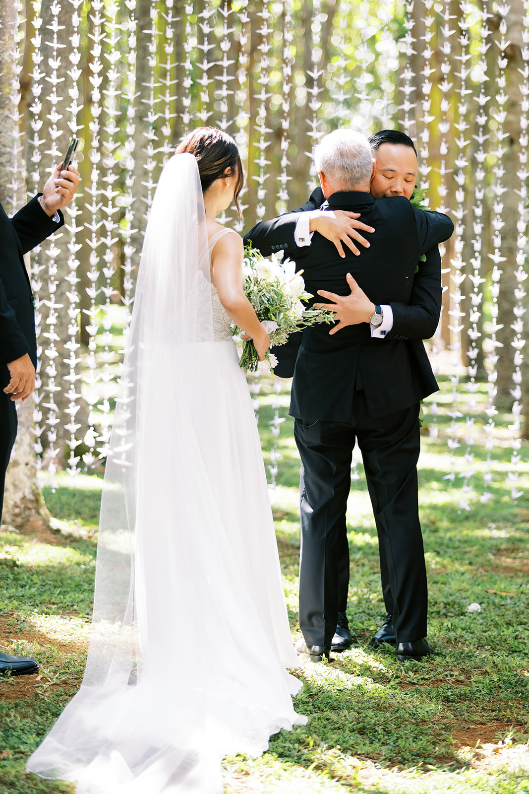 Groom embracingthe bride's father during their Oahu Wedding ceremony captured by Oahu Wedding Photographer