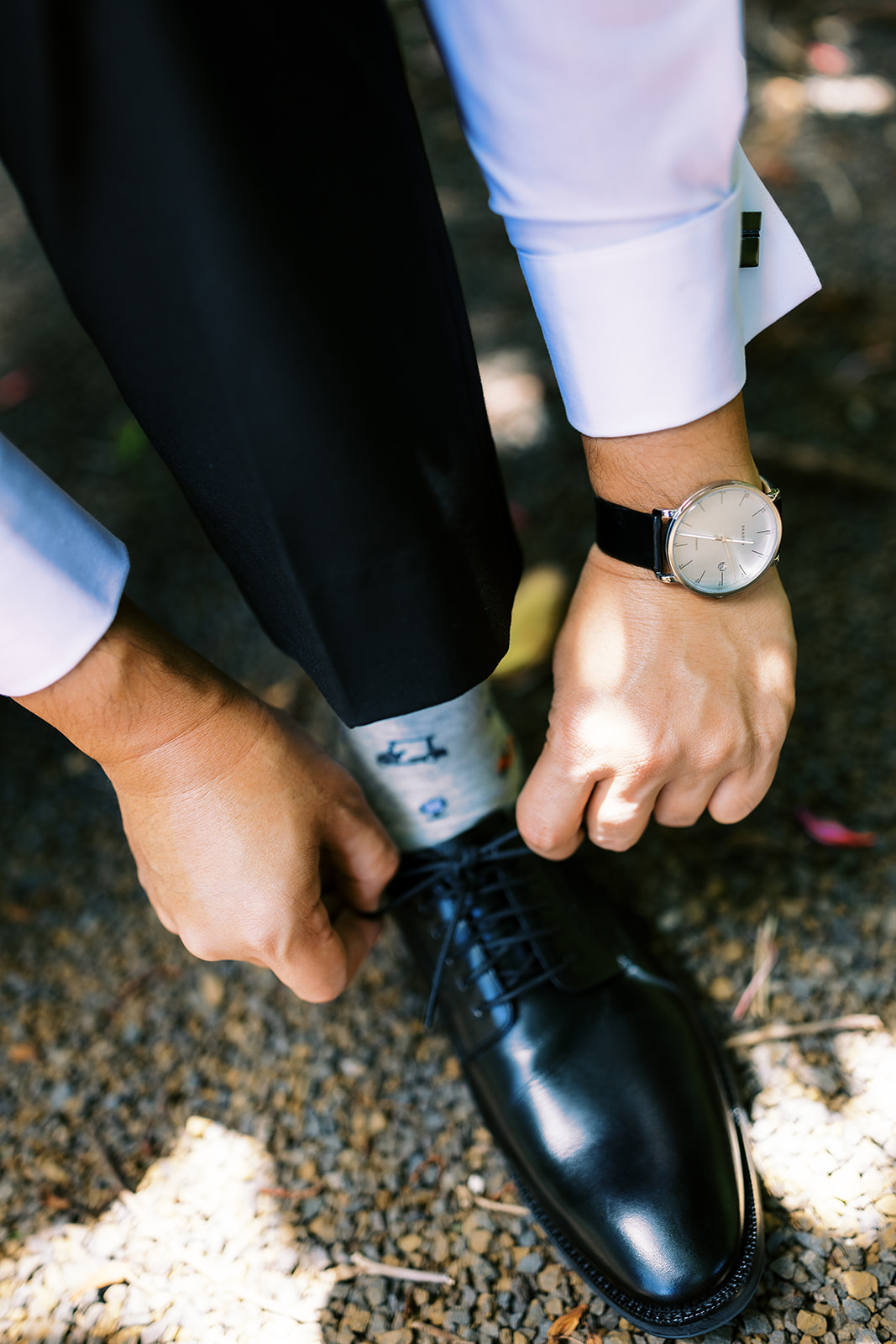 Man adjusting his socks while showcasing a watch and dress shoe Wedding at Na ‘Āina Kai Botanical Gardens
