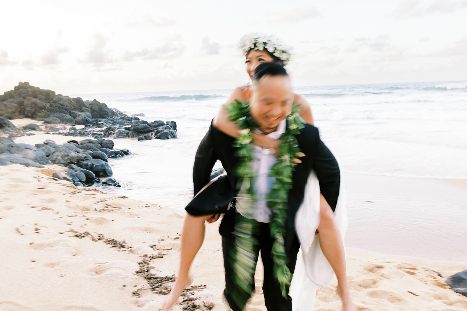 Newlyweds enjoying a playful moment on a beach Wedding at Na ‘Āina Kai captured by Oahu Wedding Photographer