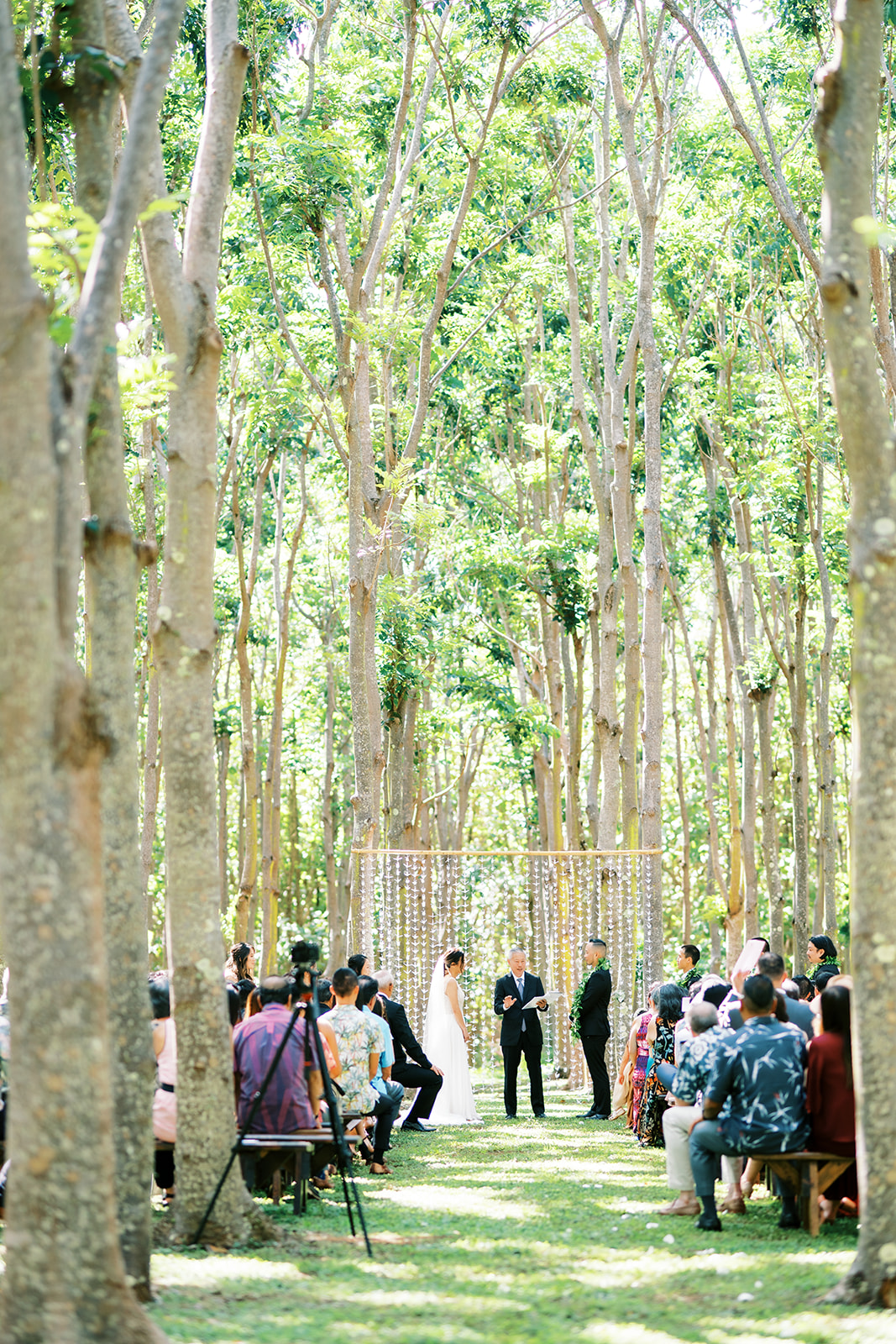 Outdoor Oahu Wedding at Na Aina Kai with guests seated and a couple standing at the altar captured by Megan Moura