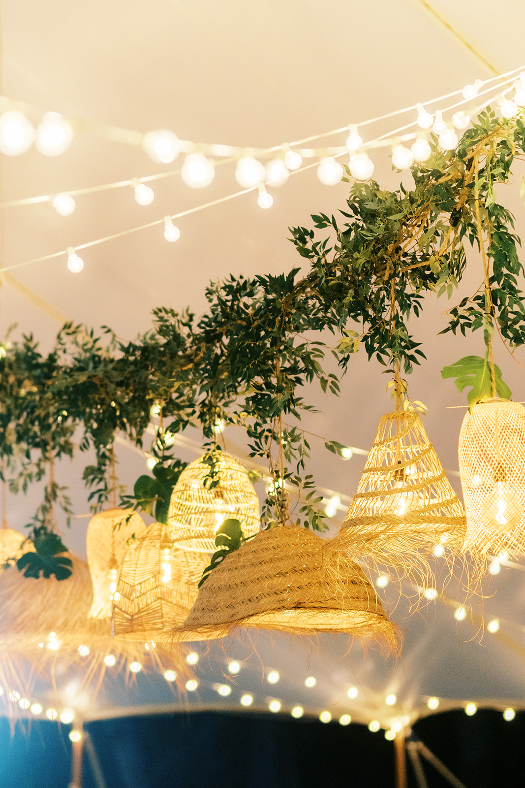 String lights and woven pendant lamps decorated with greenery under a tent Wedding at Na Aina Kai