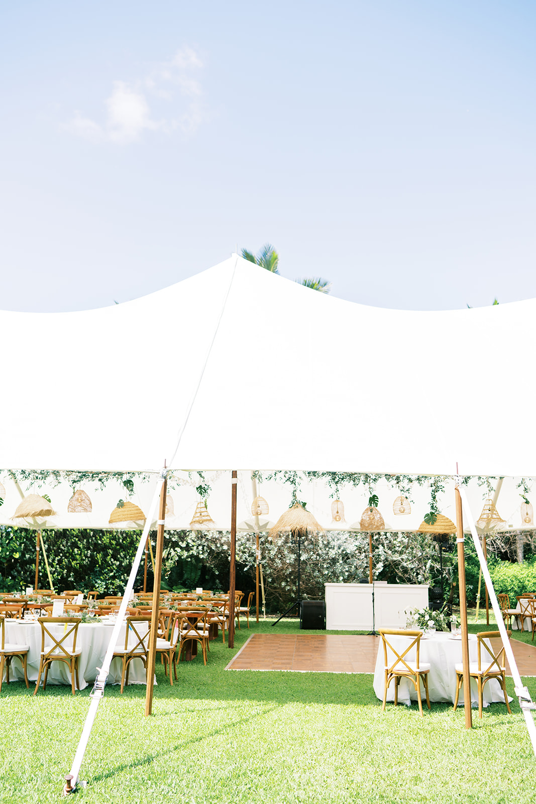 White tent with seating and a dance floor set up on a lawn for a Hawaii wedding at Na Aina Kai