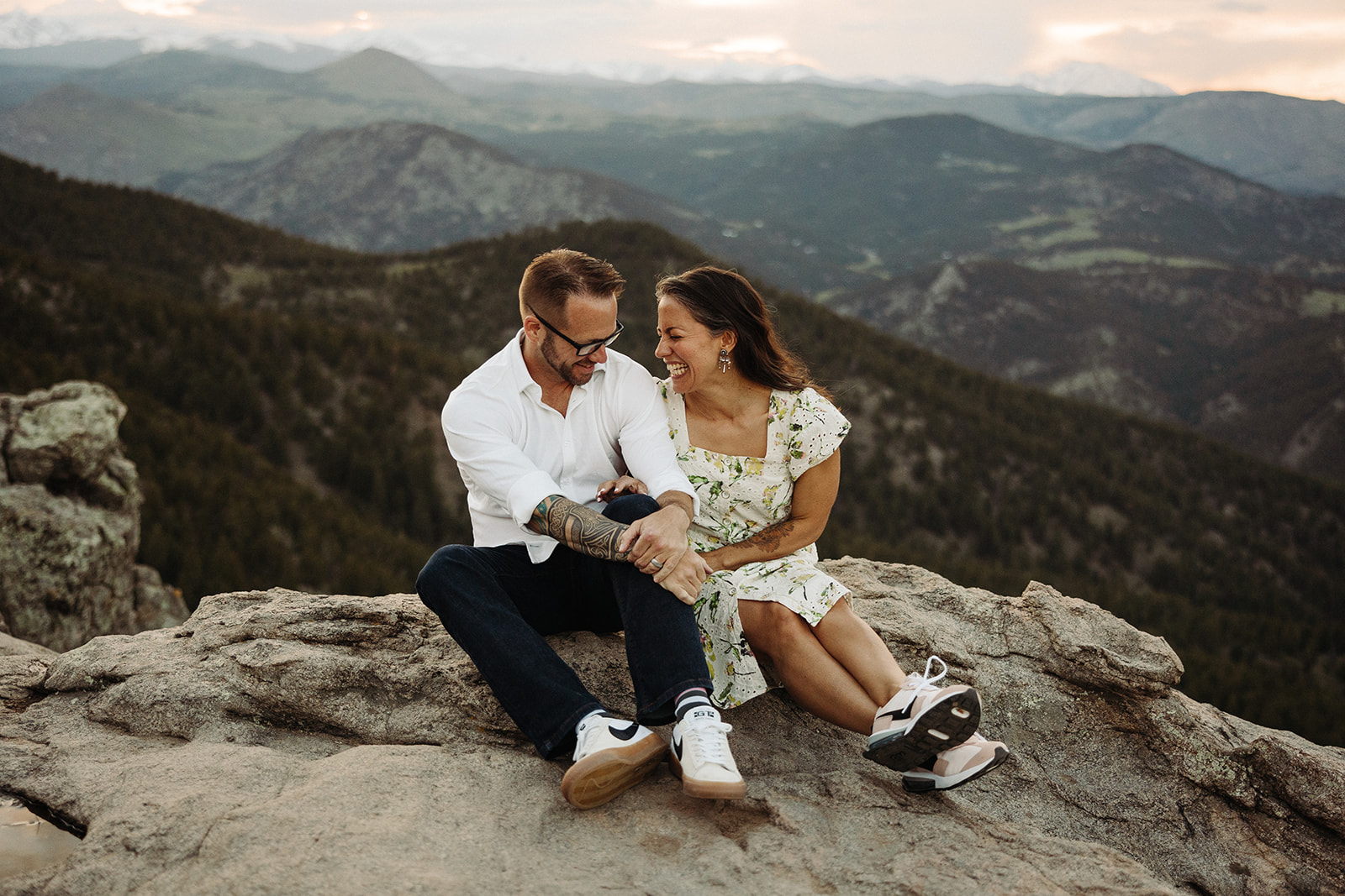 Couple sitting on a mountain smiling 
