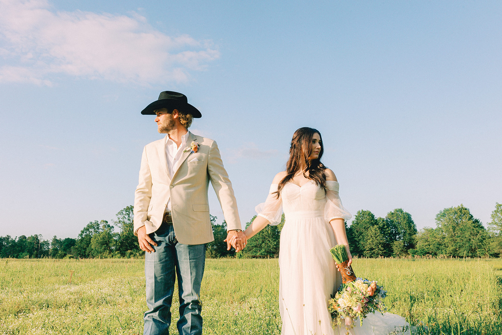 A couple who got married at Tree Haven in Simms, TX hold hands in the field