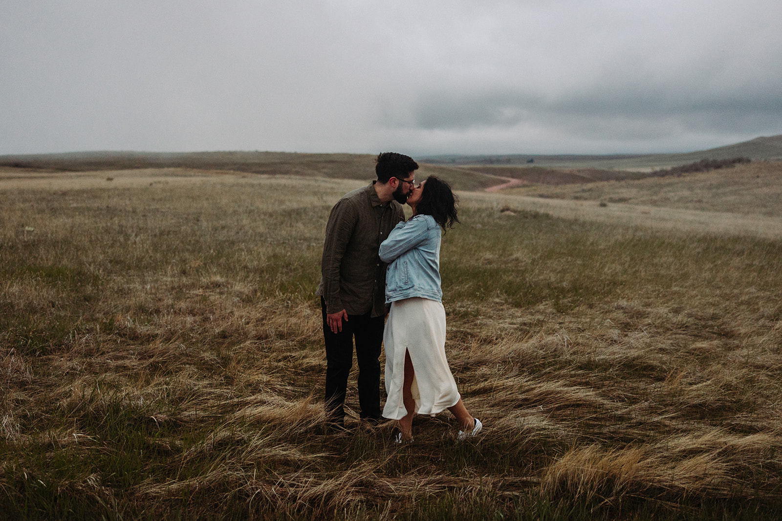 Man and woman kissing in a field during their Mountain Engagement 