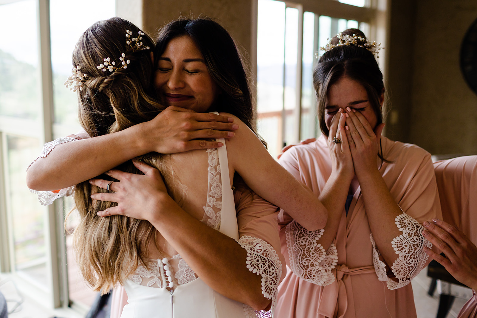 Bridesmaids get emotional and hug the bride when they see her fully dressed for the wedding.