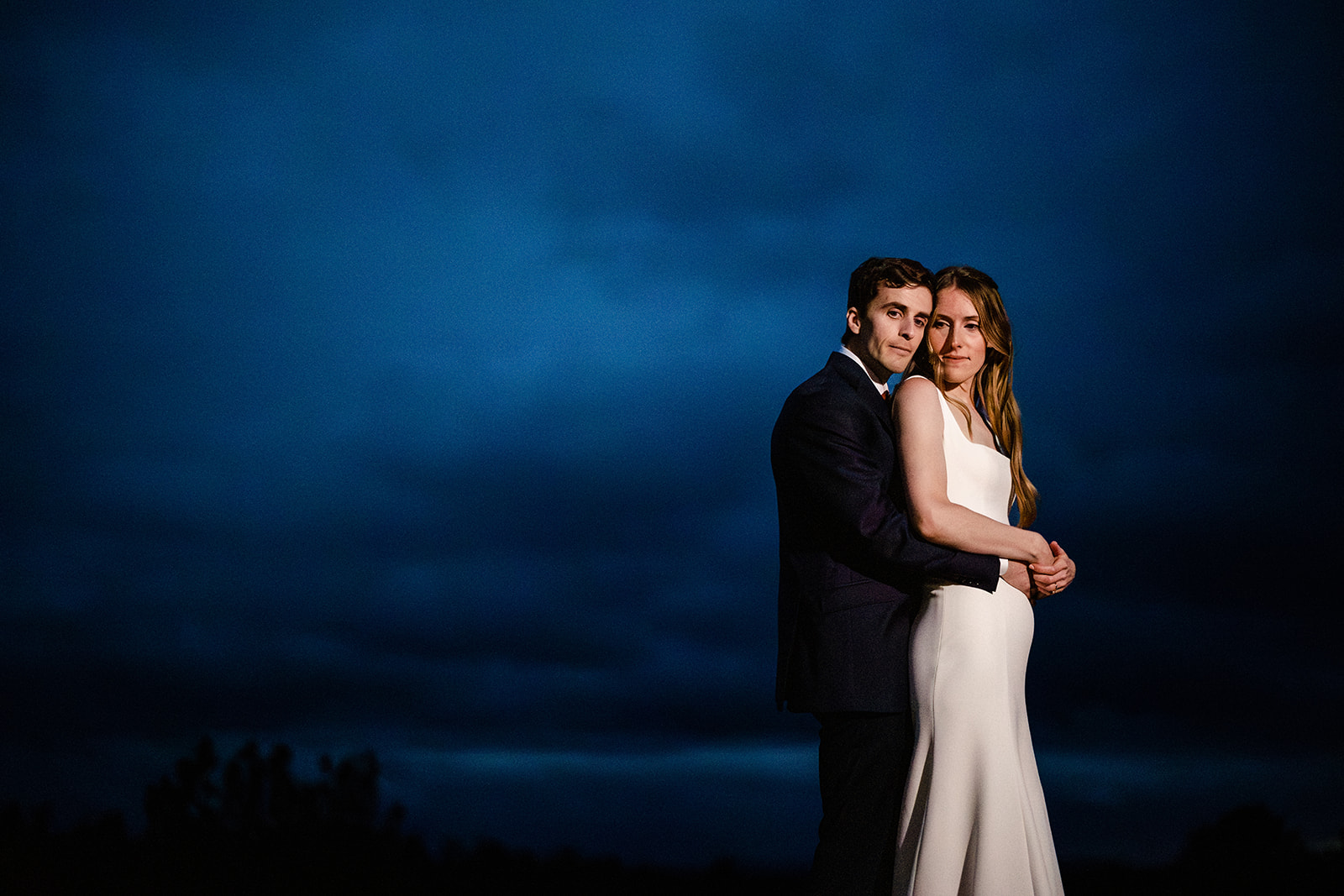 Night Portrait of Bride and Groom against a deep blue sky.