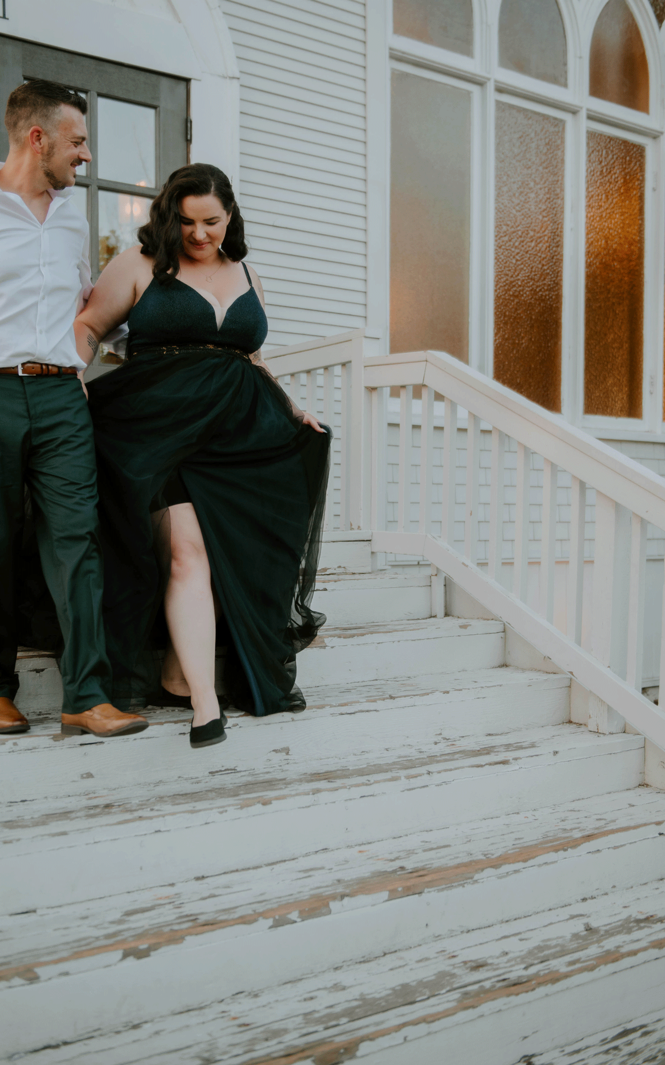A bride in a black wedding dress walking down the stairs of Grace and Hammer with her groom.