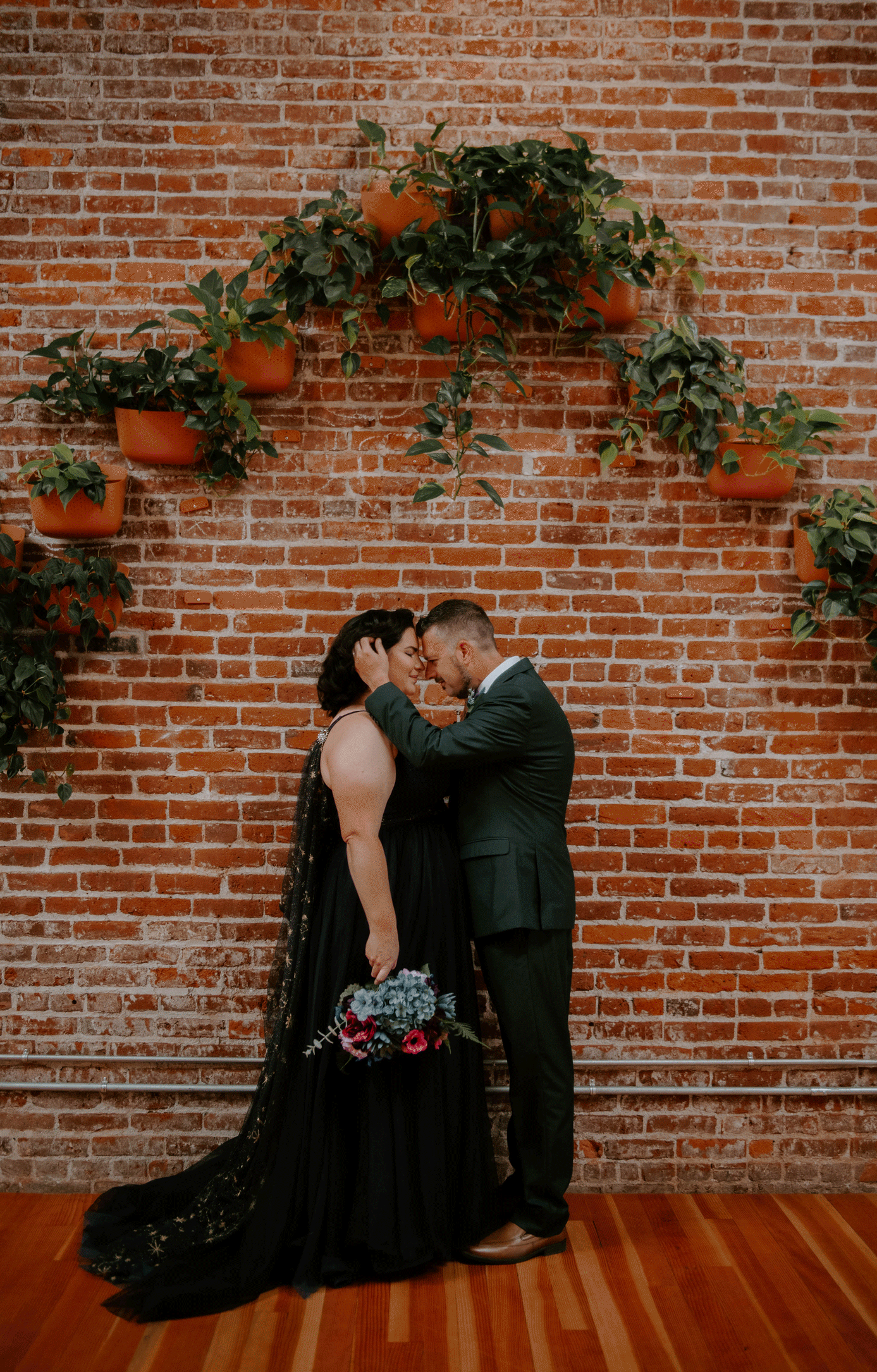 Bride and groom kissing against a brick wall at SCP hotel after their first look.