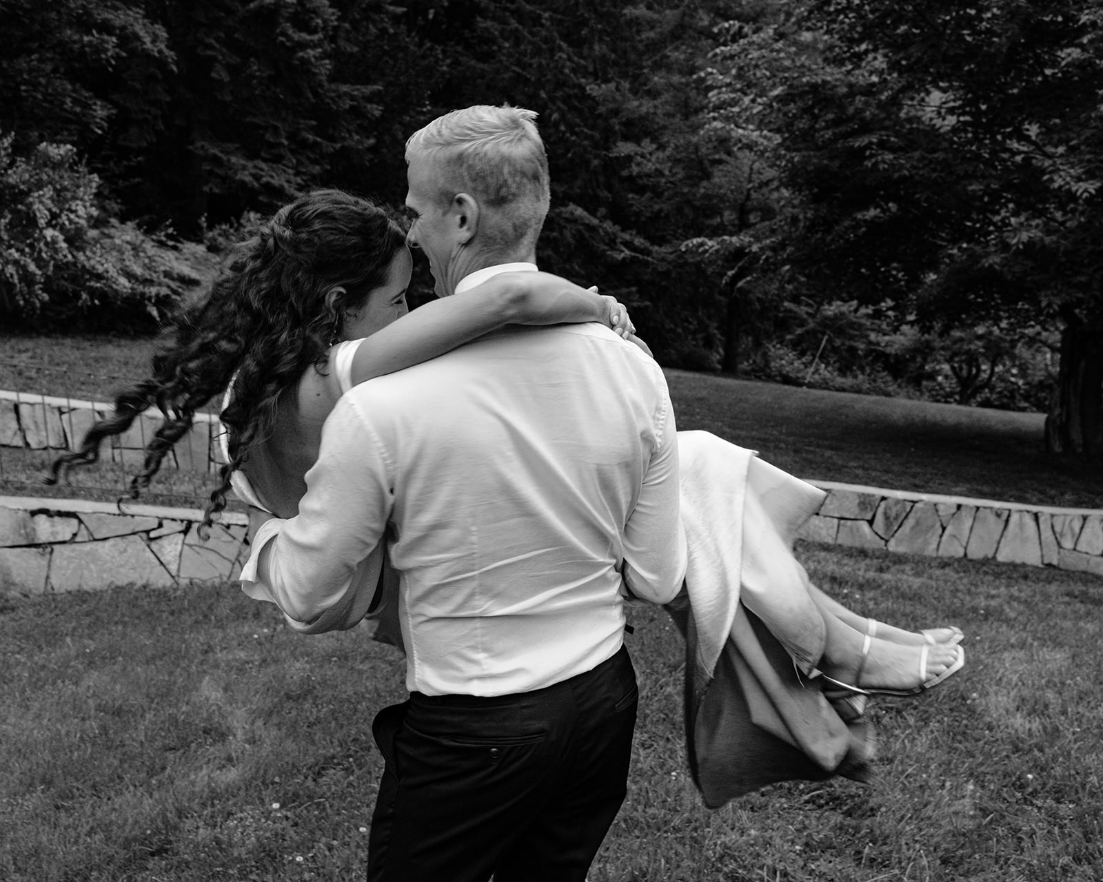 Groom playfully swings bride in his arms after their Blaylock Mansion wedding in Nelson BC