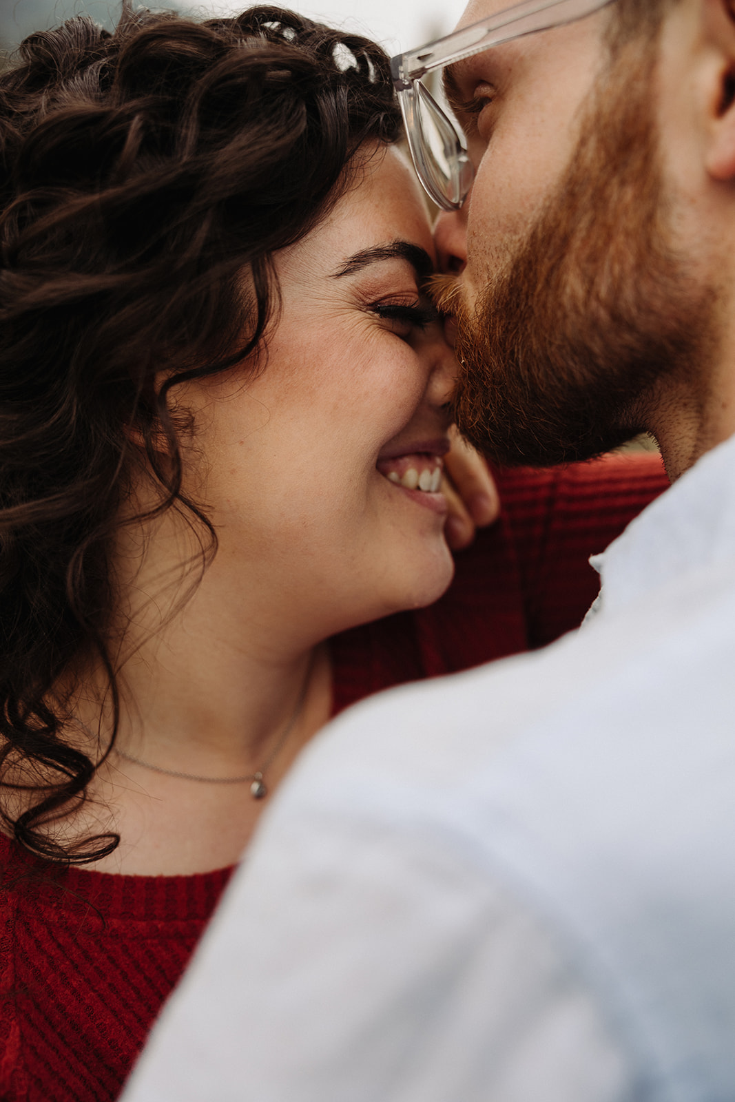 A man kissing a wonas nose while she smiles 