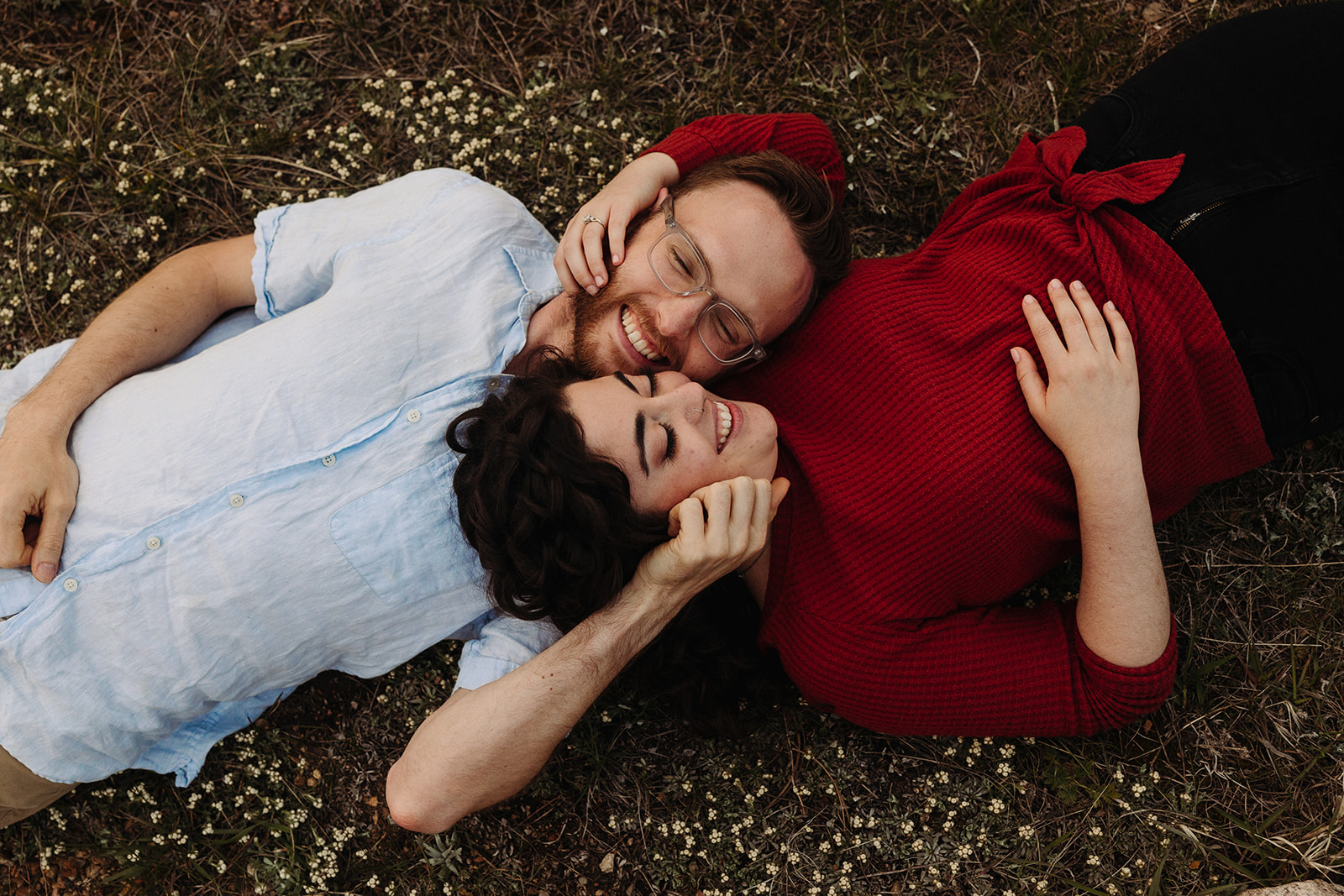 Man and woman lying on flowers for their spring engagement photos