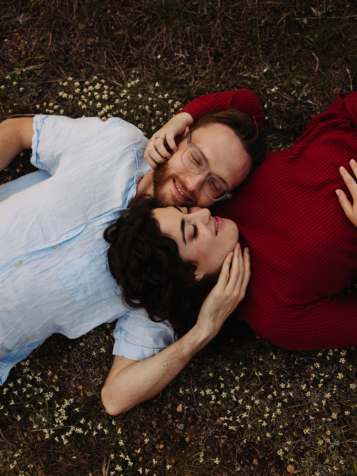 Man and woman lying on flowers for their spring engagement photos