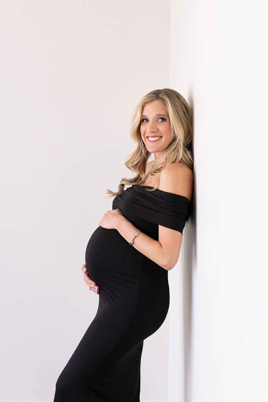 Black maternity off the shoulder dress showing off the baby bump
