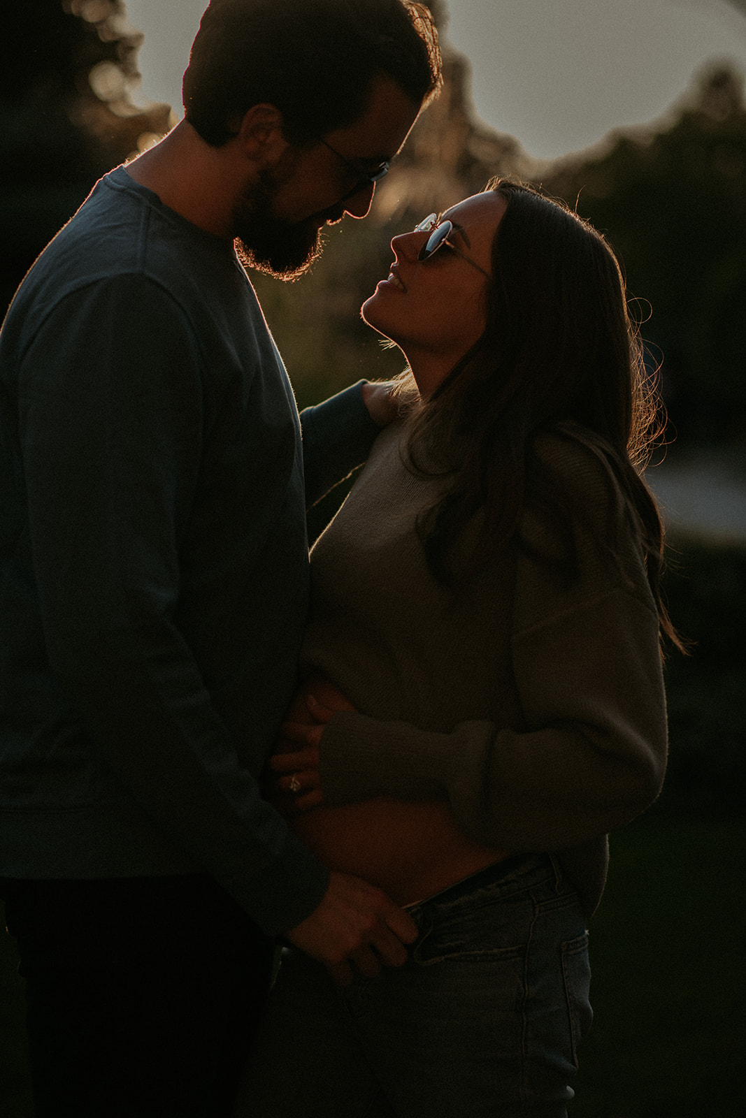Expecting parents kiss in twilight for some outdoor maternity photos