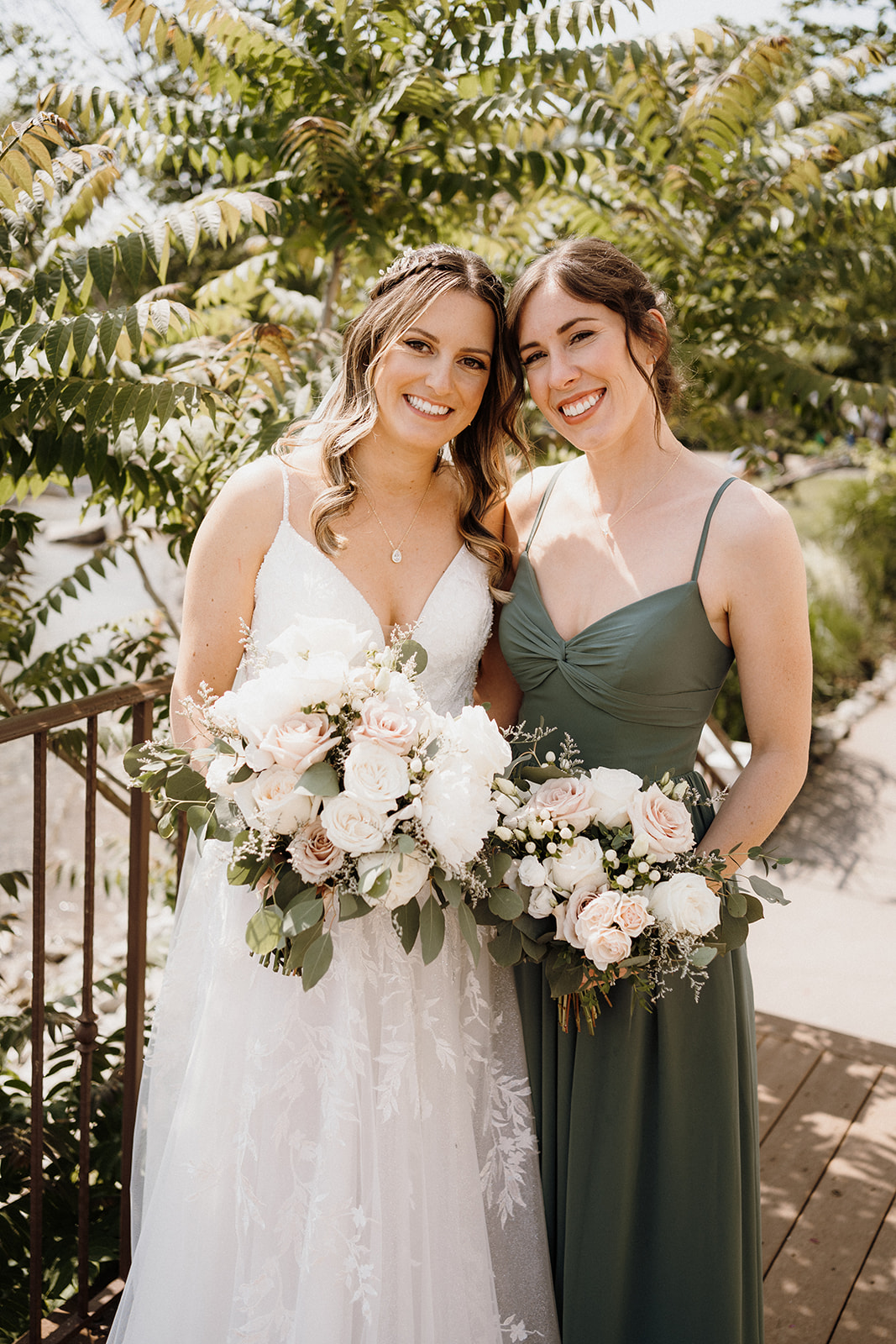 Bride stands with bridesmaid outside.