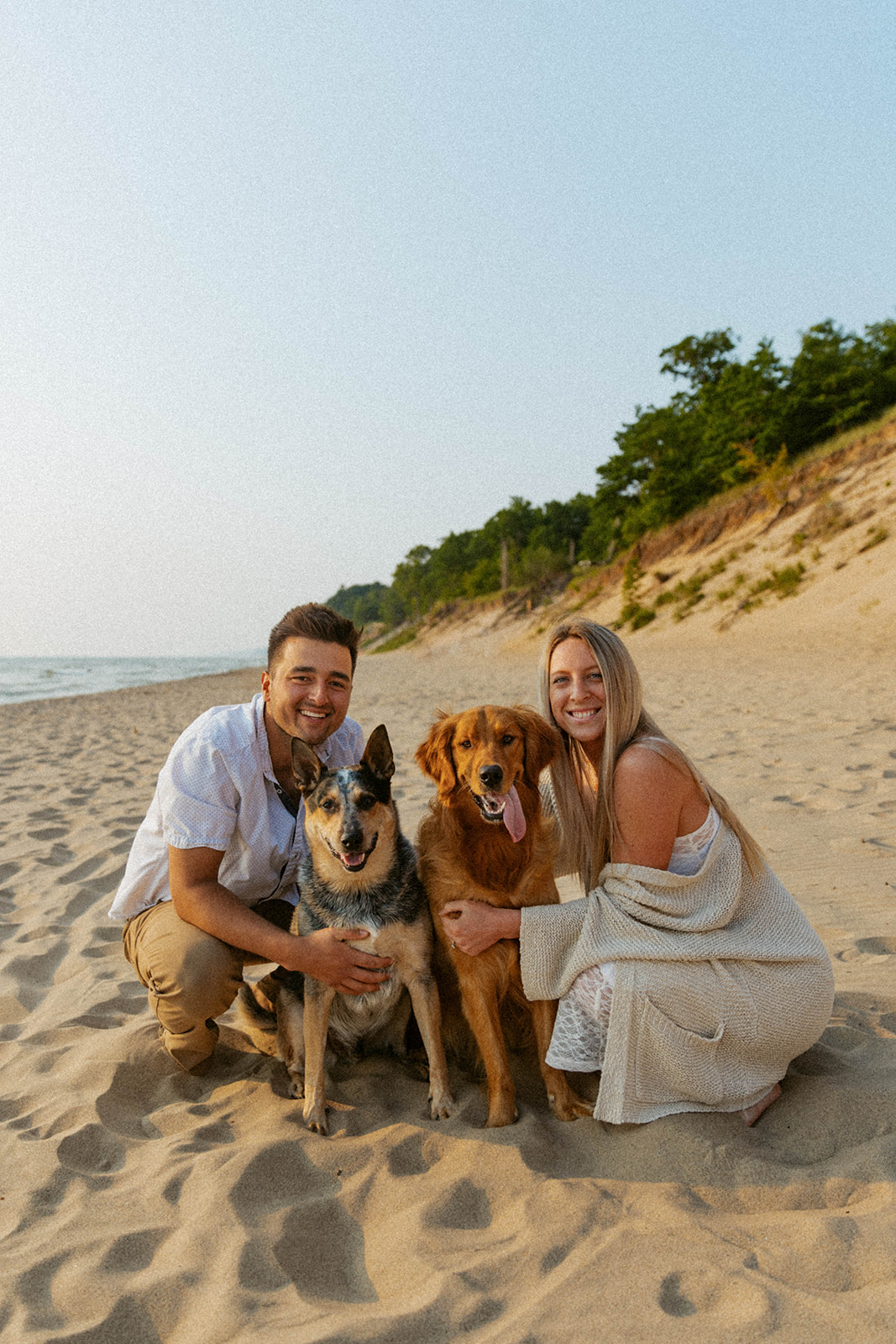 couple poses together with their two dogs at kirk park beach