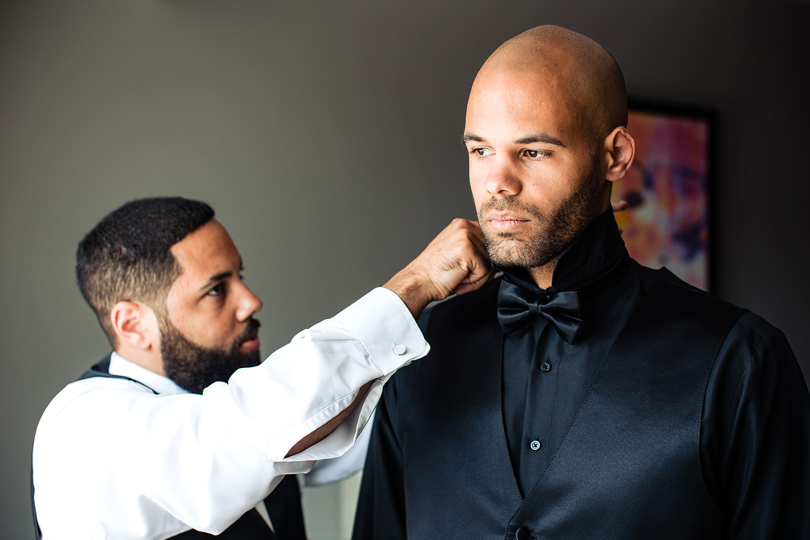 best man helping a groom put on his shirt