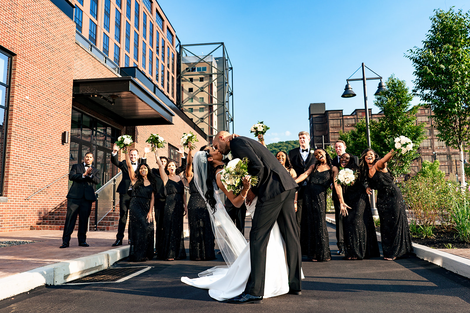 bridal party cheering as bride and groom kiss outside of wind creek event center wedding