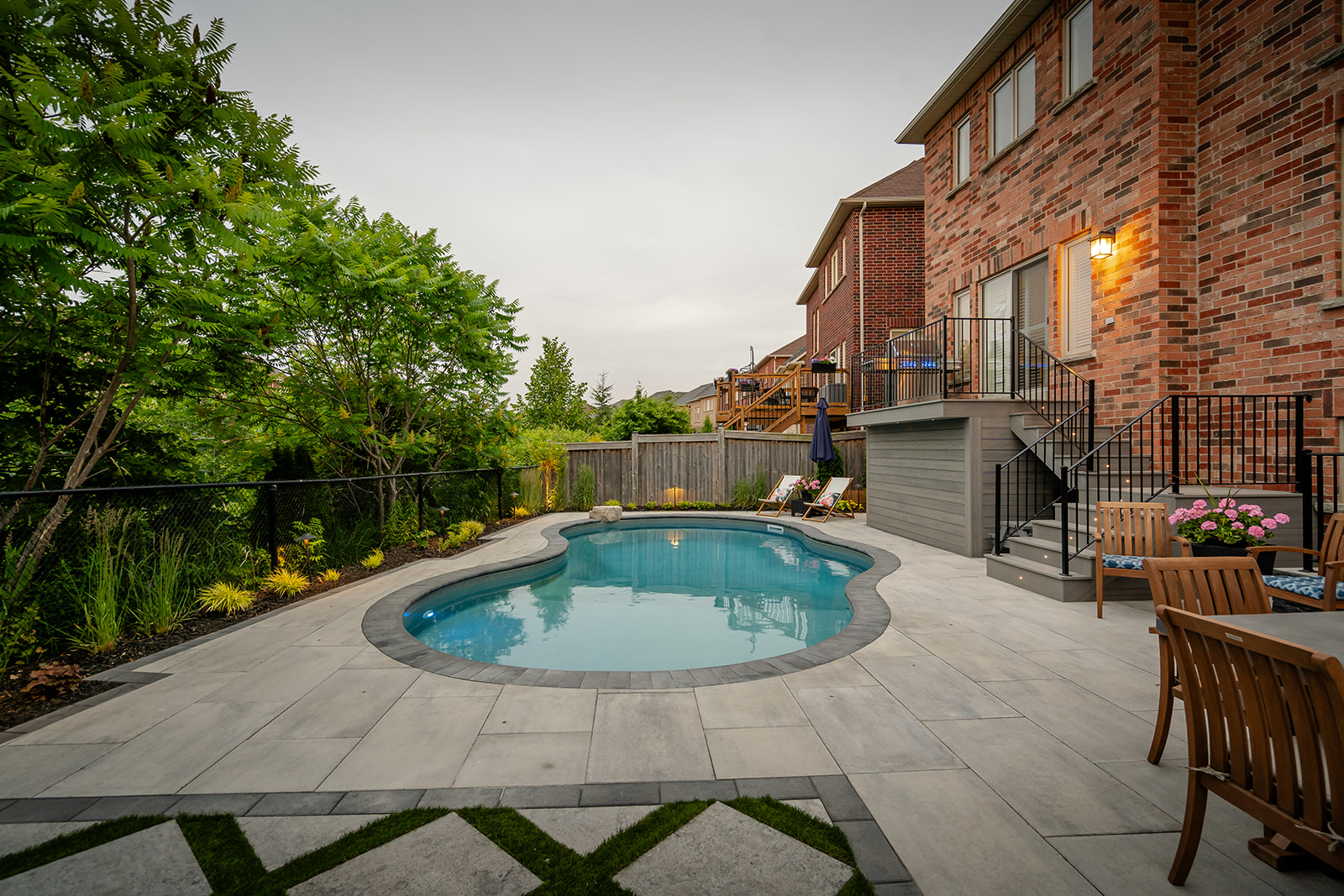 An inground pool in the middle of the yard with patio stones surrounding.