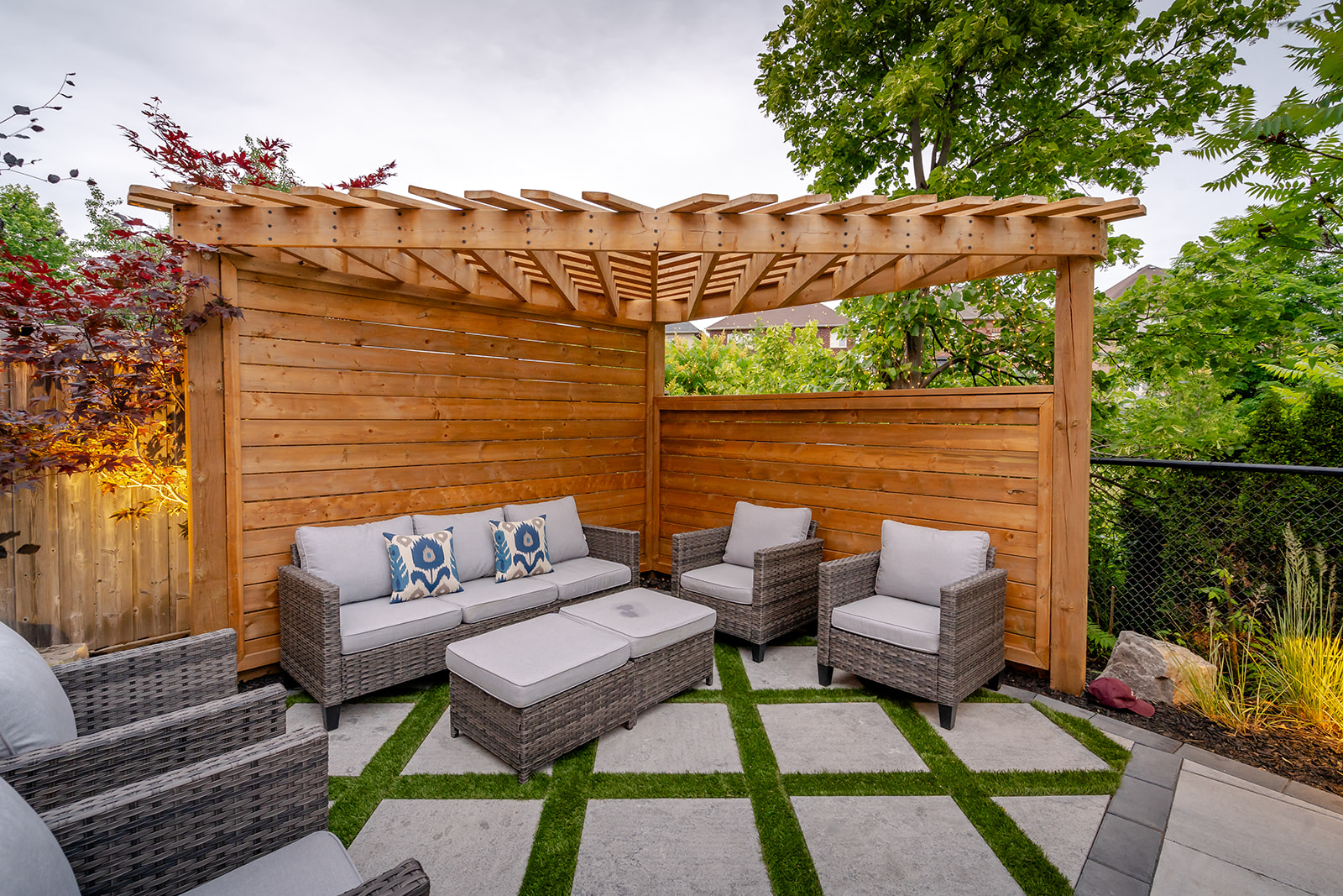 An outdoor patio set on top of patio stones with a wooden canopy overhead.