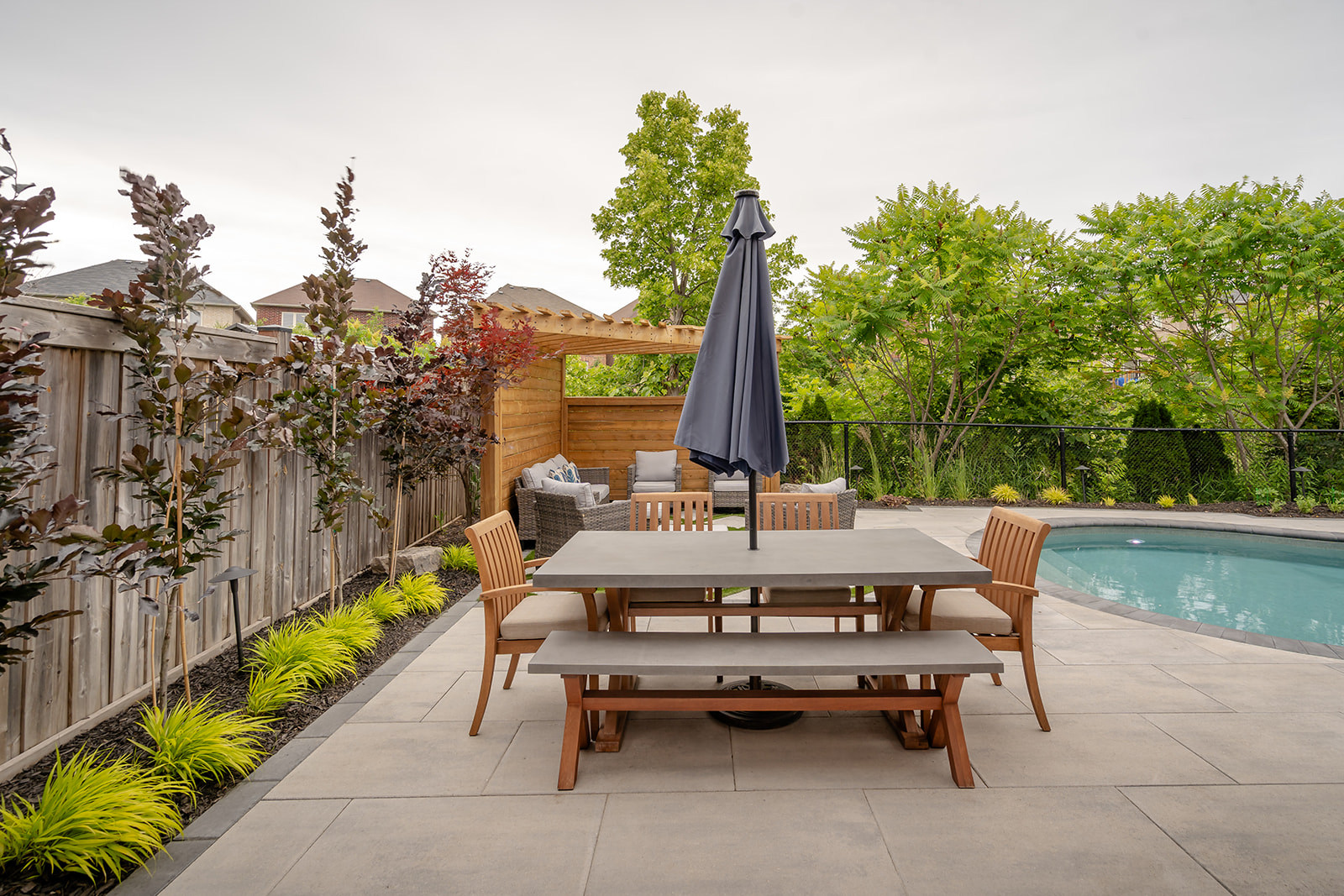 An outdoor table with an inground pool off to the side.