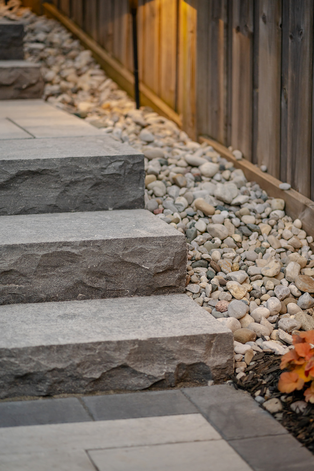 Stairs leading upward toward the front of the house with pebbles lining the edge of the property.