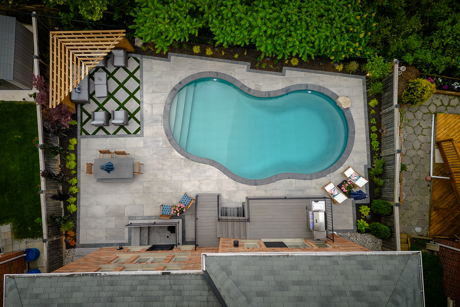 Top-down view of an inground pool, outdoor patio set surrounded by interlocking blocks.