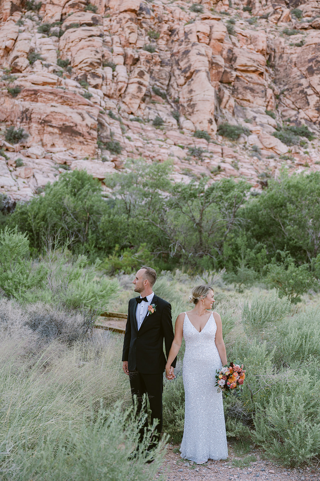 bride and groom posing on Red Rock Boardwalk with Red Rock Canyon backdrop. Bride wearing glittering white dress.