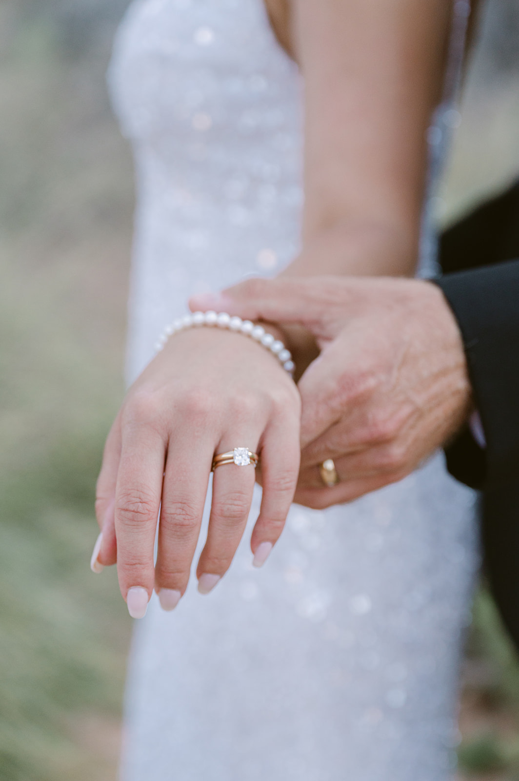 groom holding out brides hand for close up of diamond wedding ring