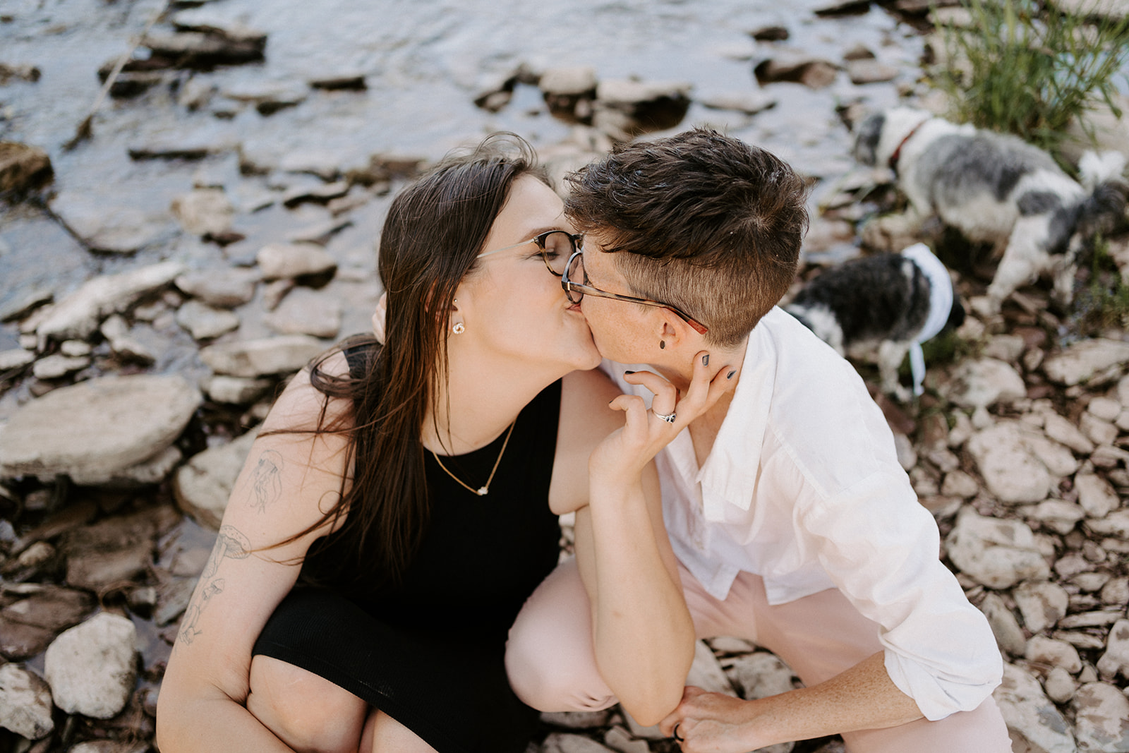 Two people sitting on rocks and kissing.