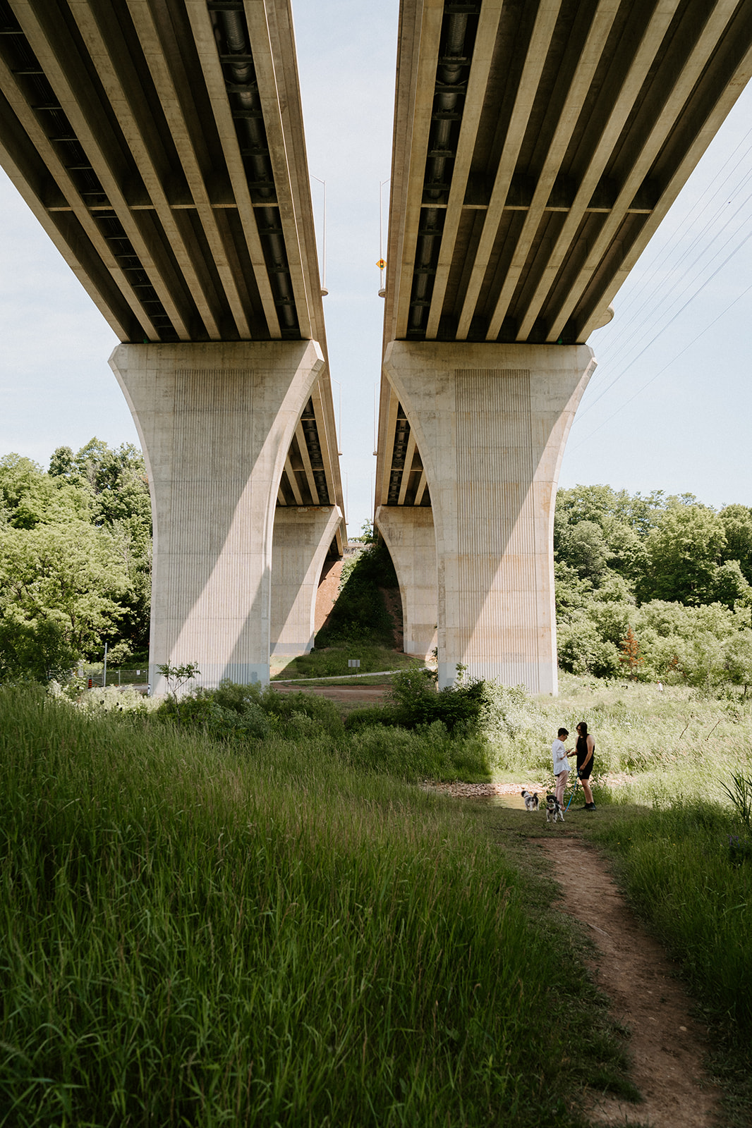 Two people standing to the side underneath an overpass.