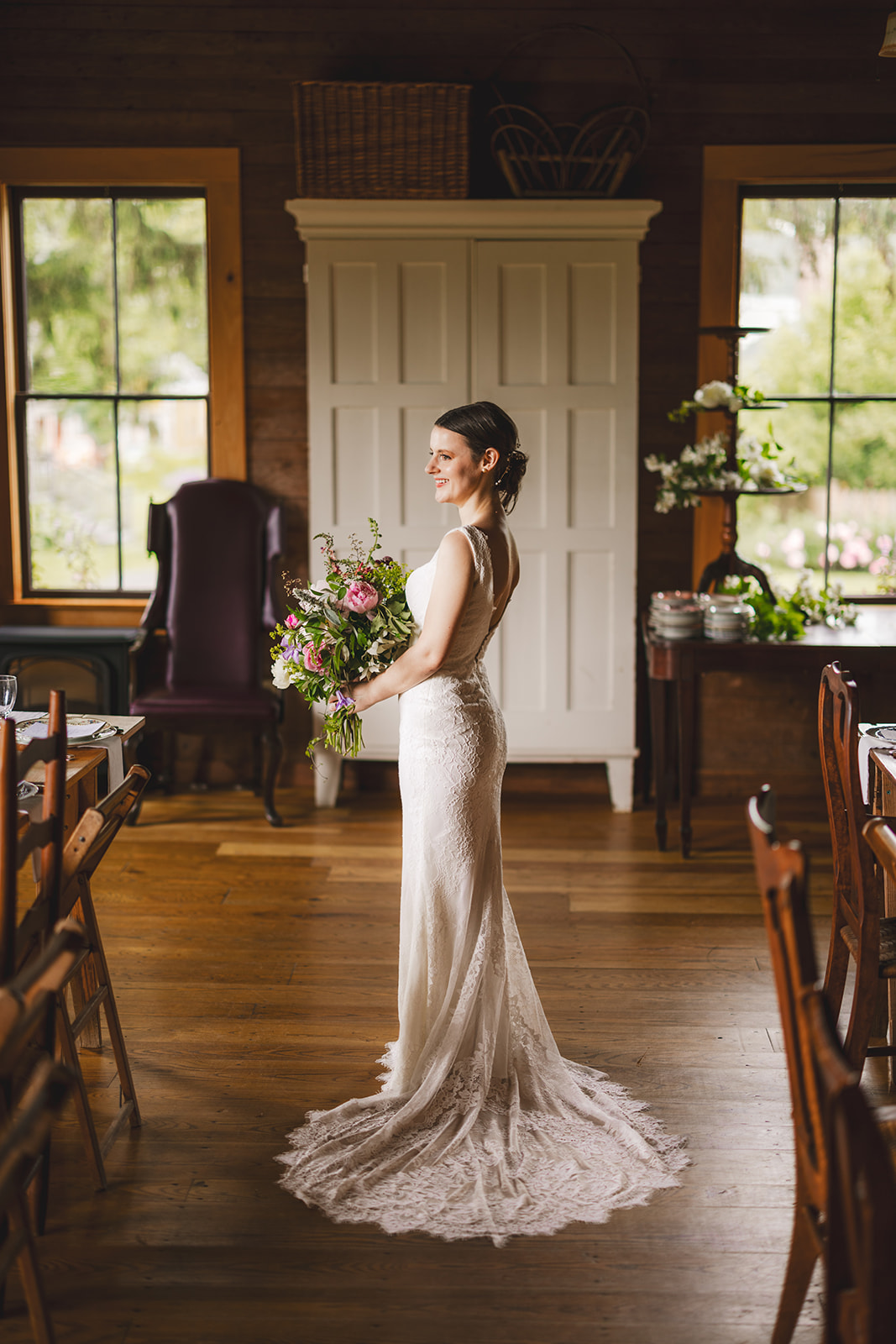 a bride in a white dress holding flowers in an old barn 