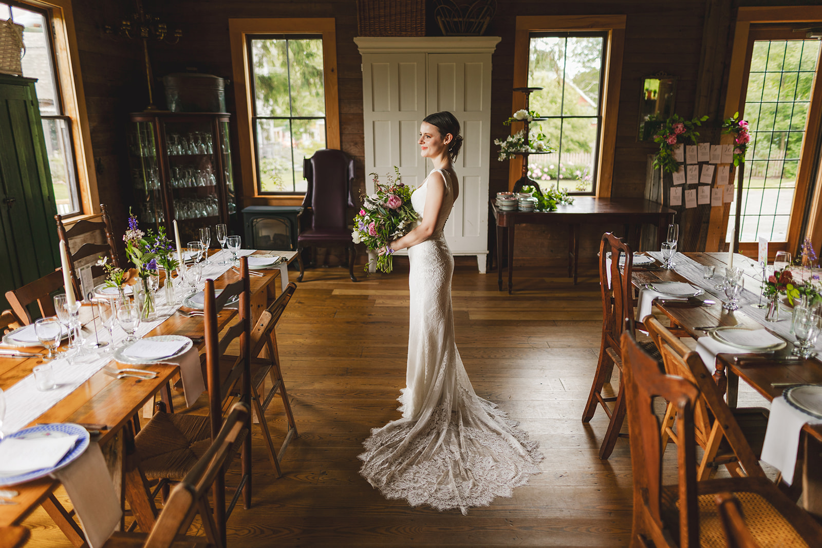 a bride in a white dress holding flowers in an old barn 