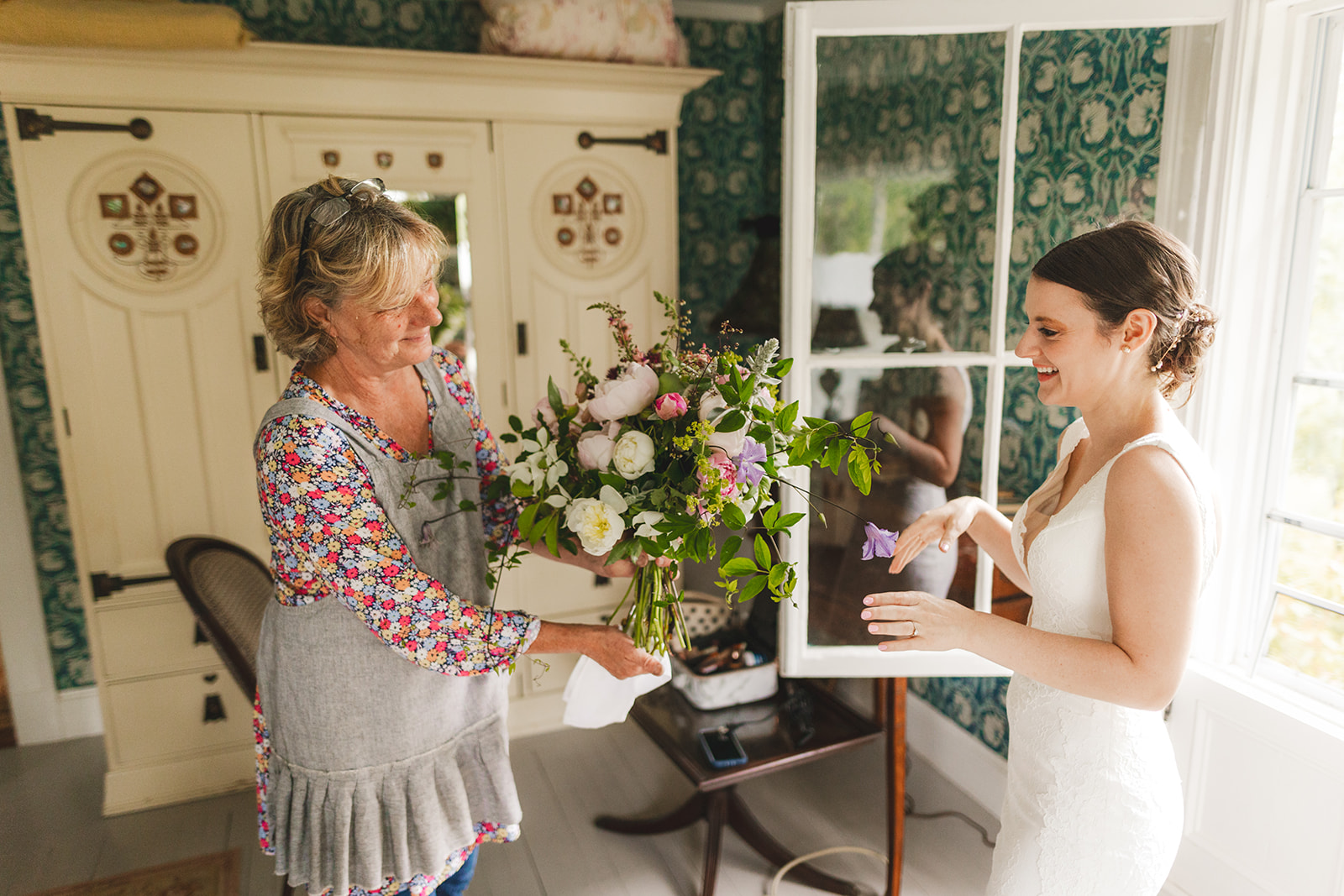 a florist hands a bride her wedding bouquet 