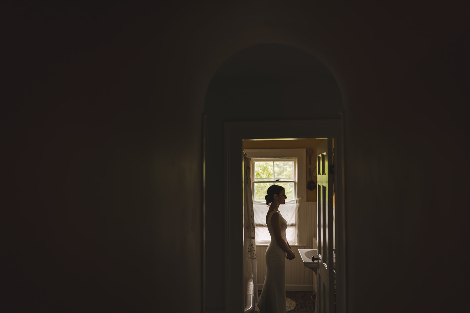 a silhouette image of a bride standing at a sink in an old home 