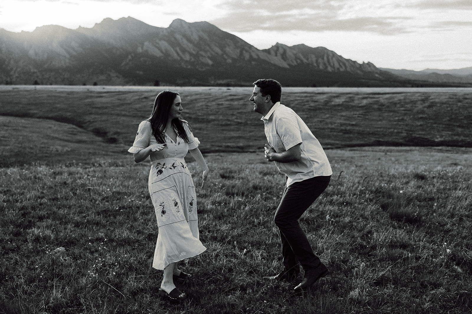 Fun couple dancing in a field nearby mountains