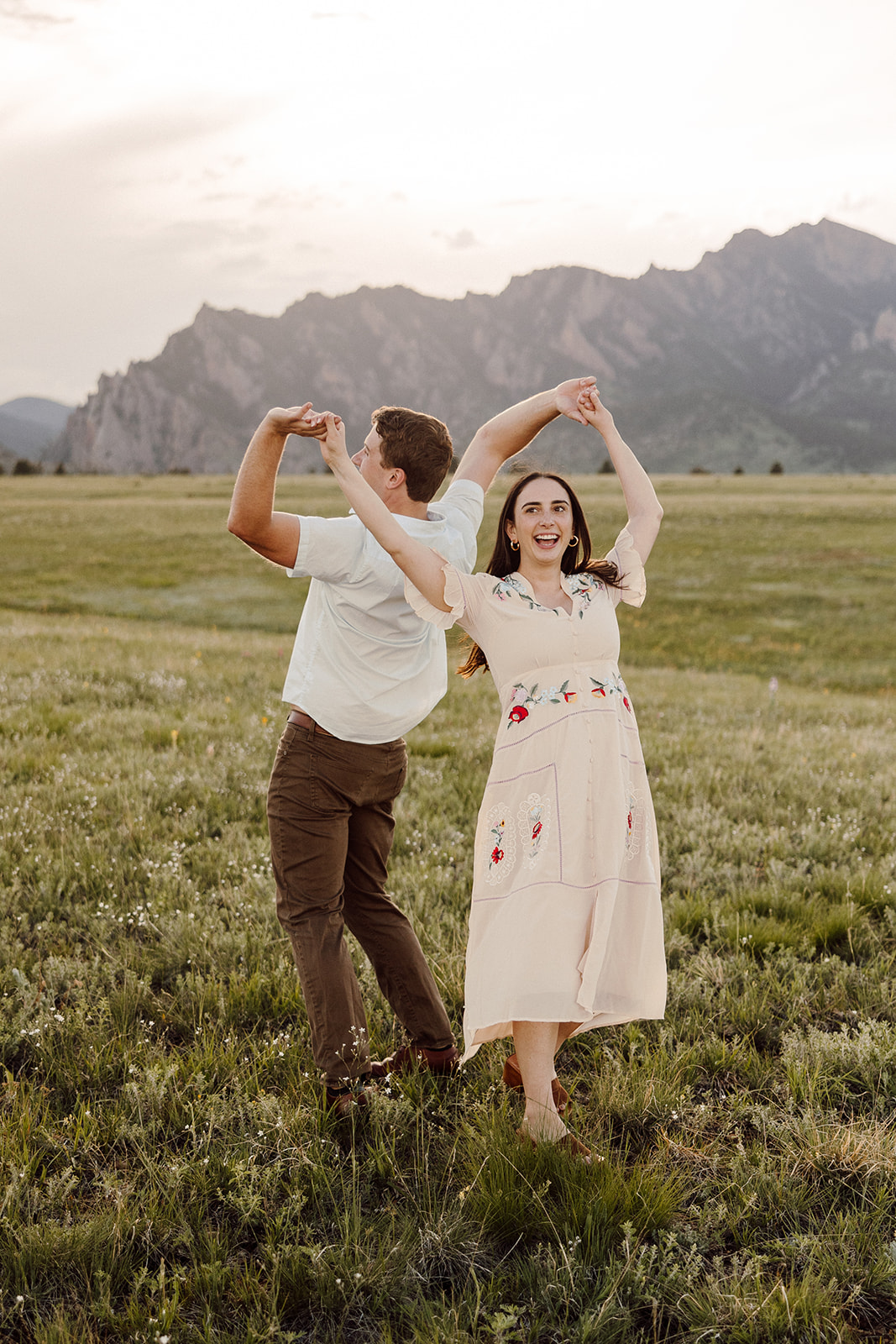 Man and woman twirling and dancing in front of picturesque mountains in Denver