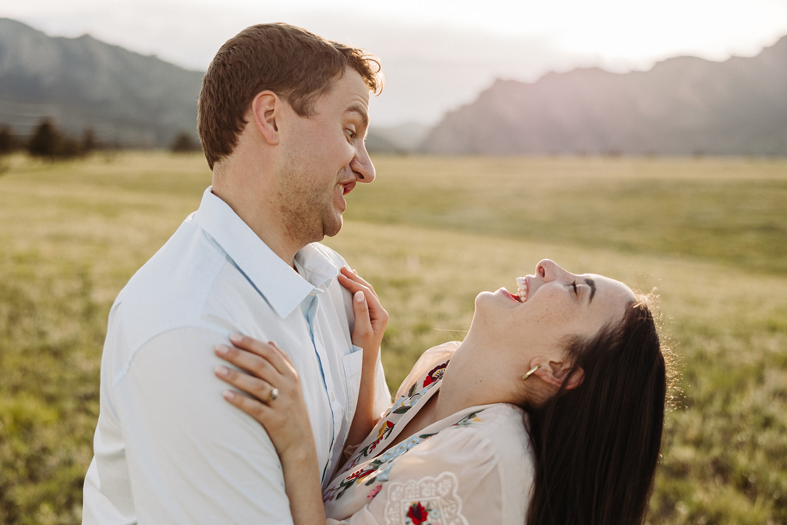 Man holding his fiance as she leans back laughing at his silly expression