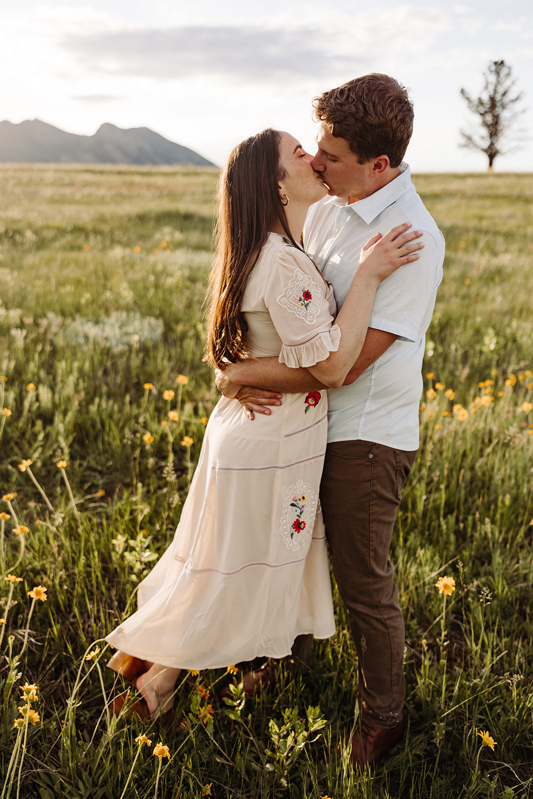 Engaged couple hugging in a field of yellow flowers during