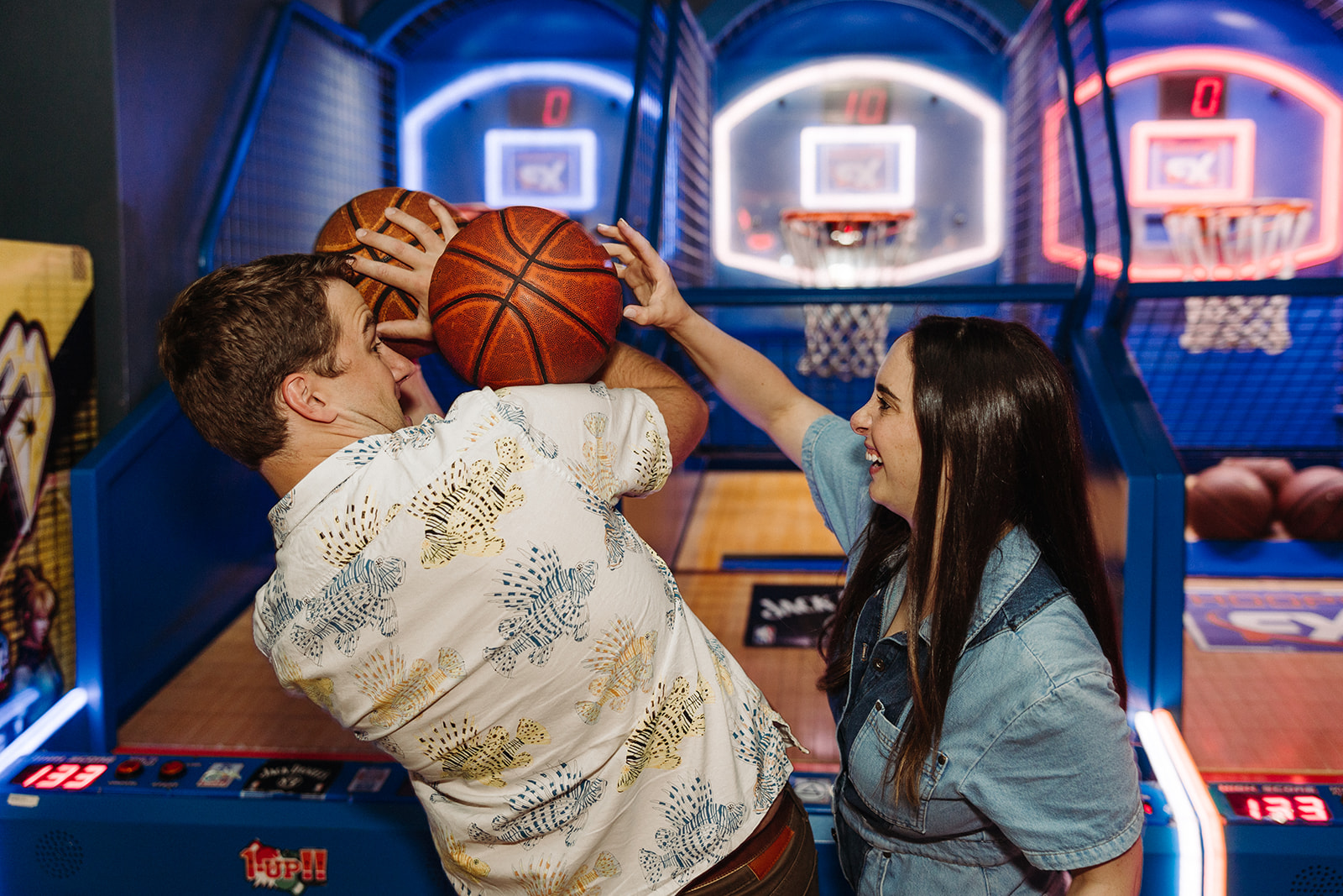 Woman playing around with her fiance as he gets ready to shoot a basketball at a Denver arcade
