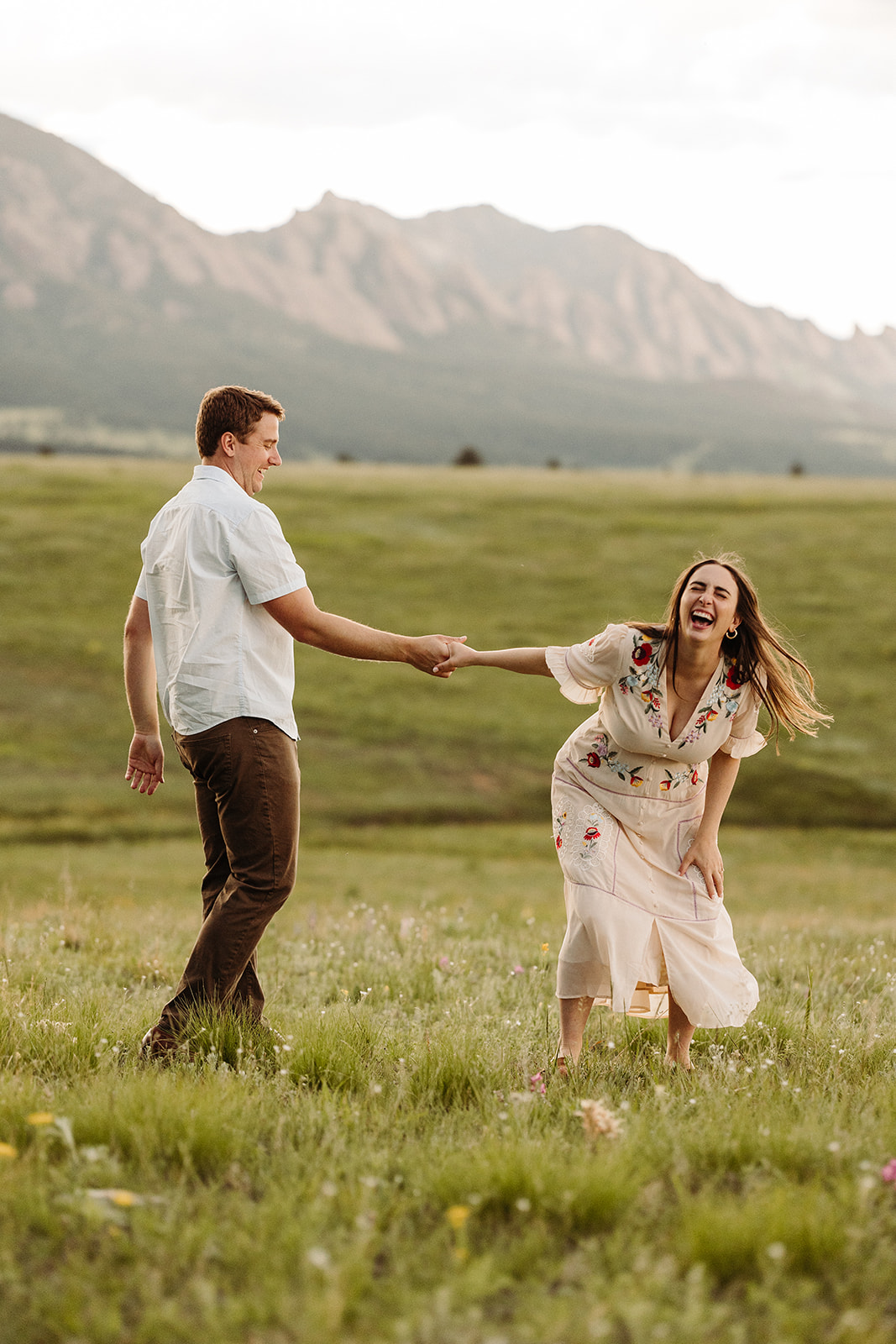 Couple pulling eachother and laughing with a stunning mountain range in the background