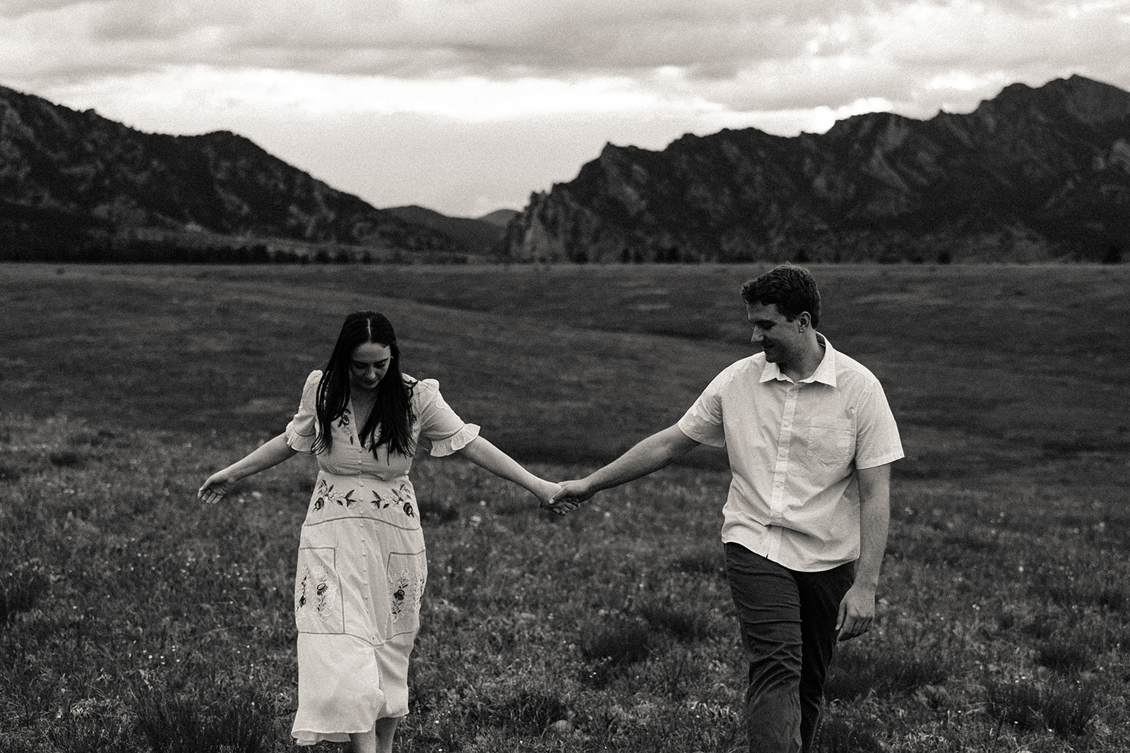 Black and white photo of two soulmates holding hands through a field of flowers in Denver