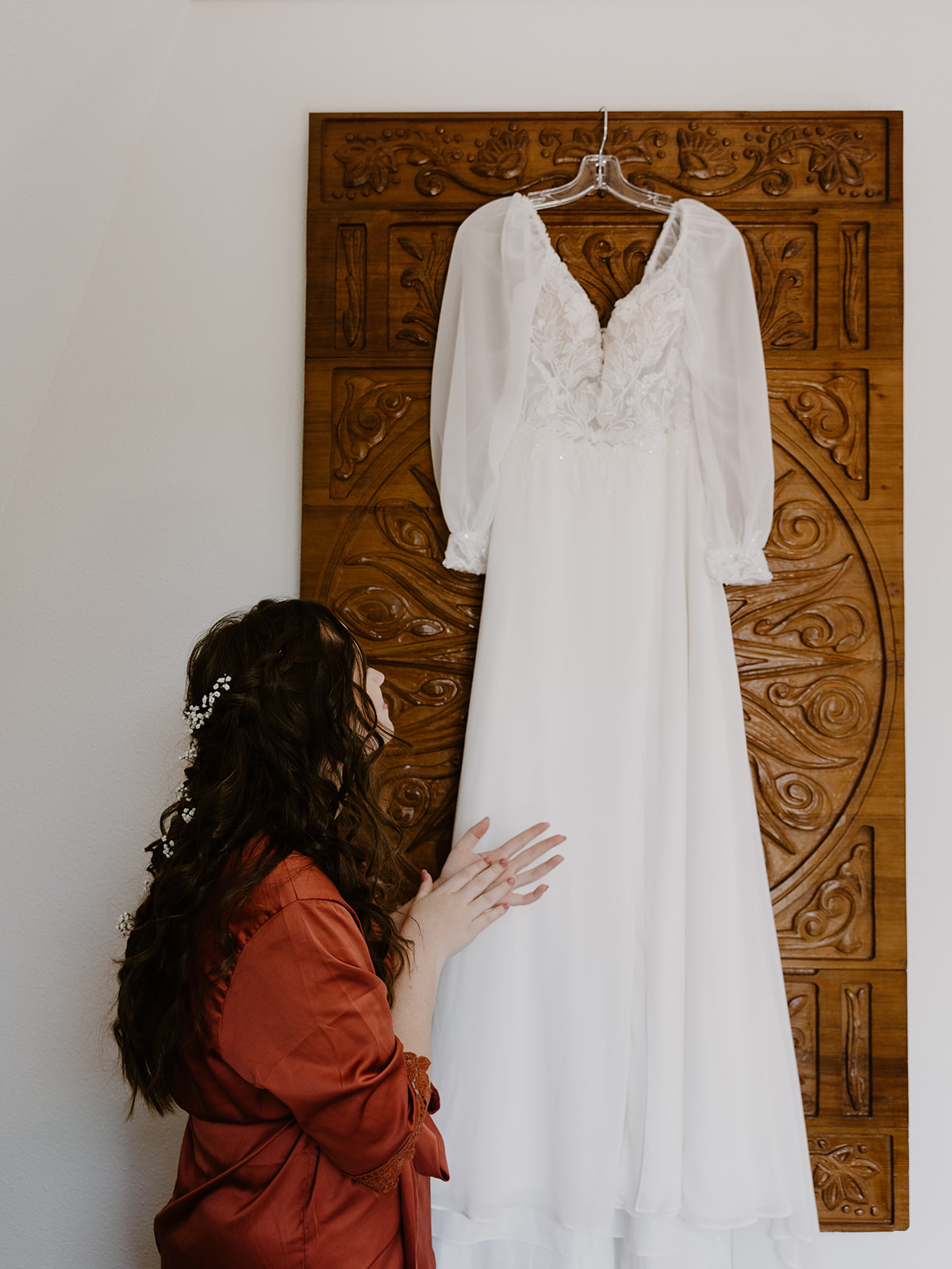 a bride looking at her wedding dress while wearing a robe
