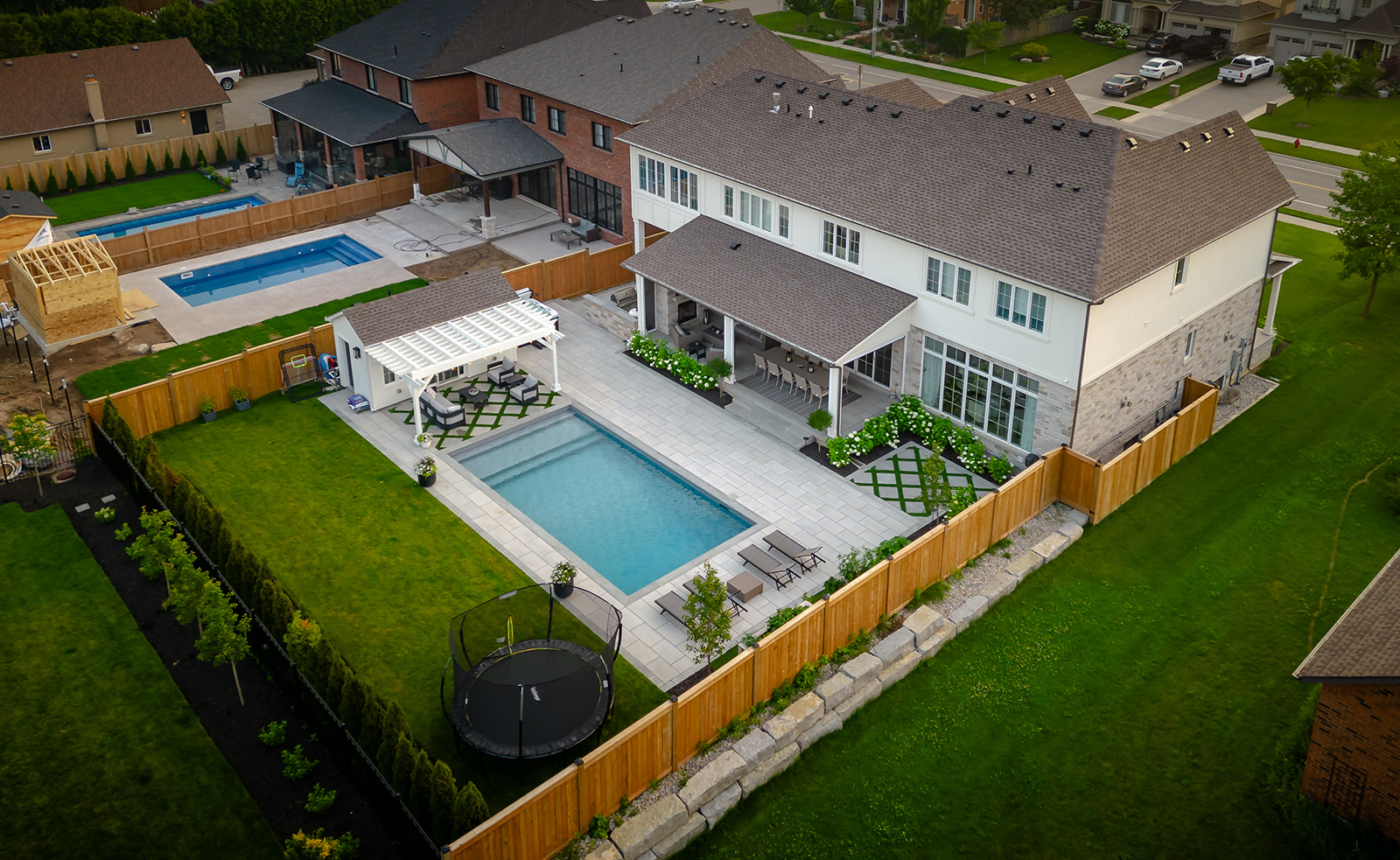Backyard with an inground pool, a trampoline, and seating on either side of the pool.