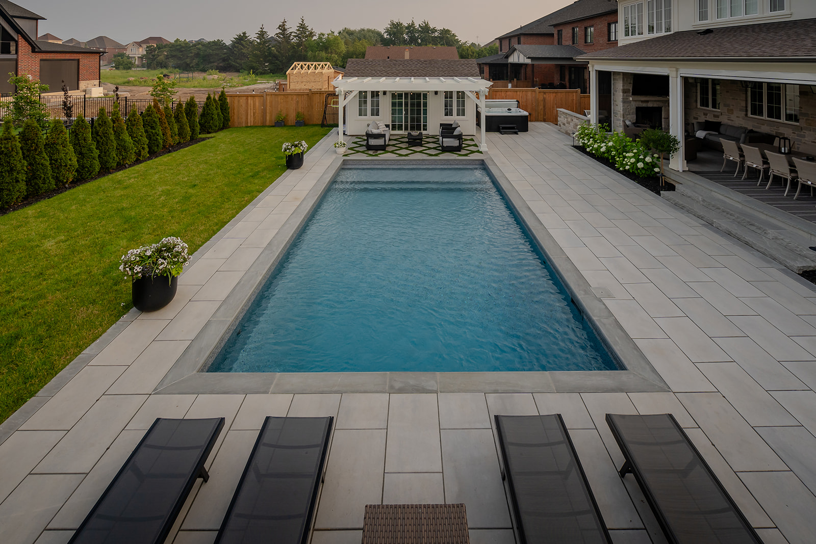 an inground pool with lounge chairs at the end of the pool.