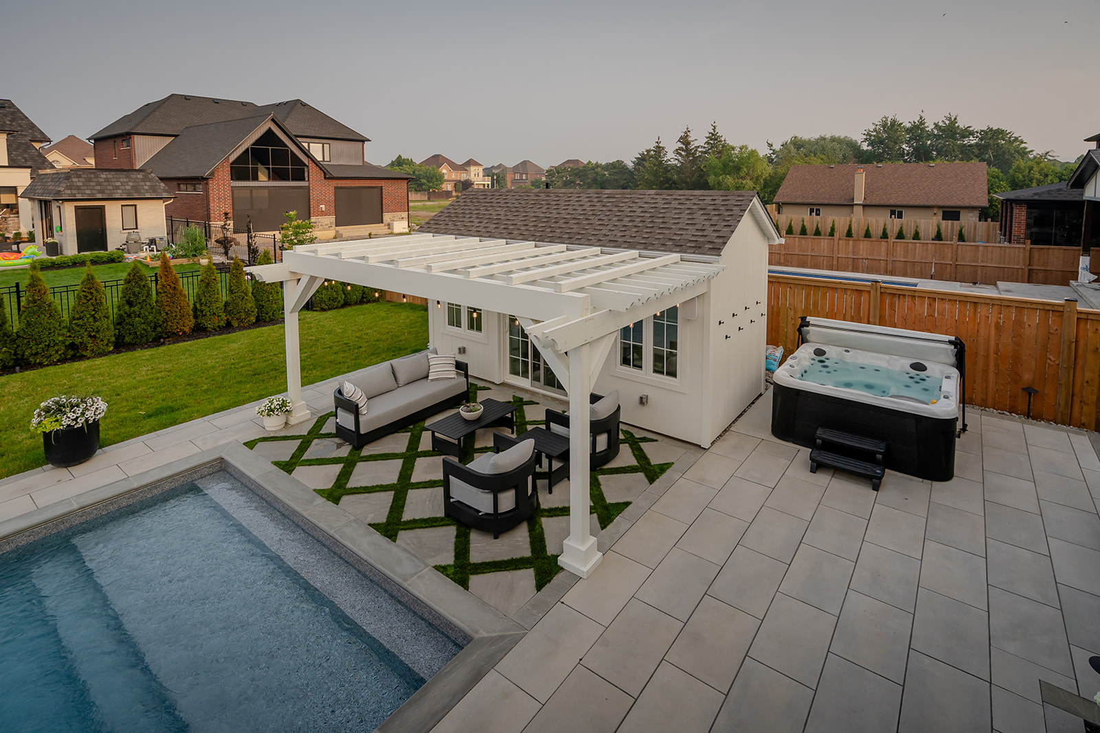 An outdoor seating area underneath a gazebo with a hot tub on the side.