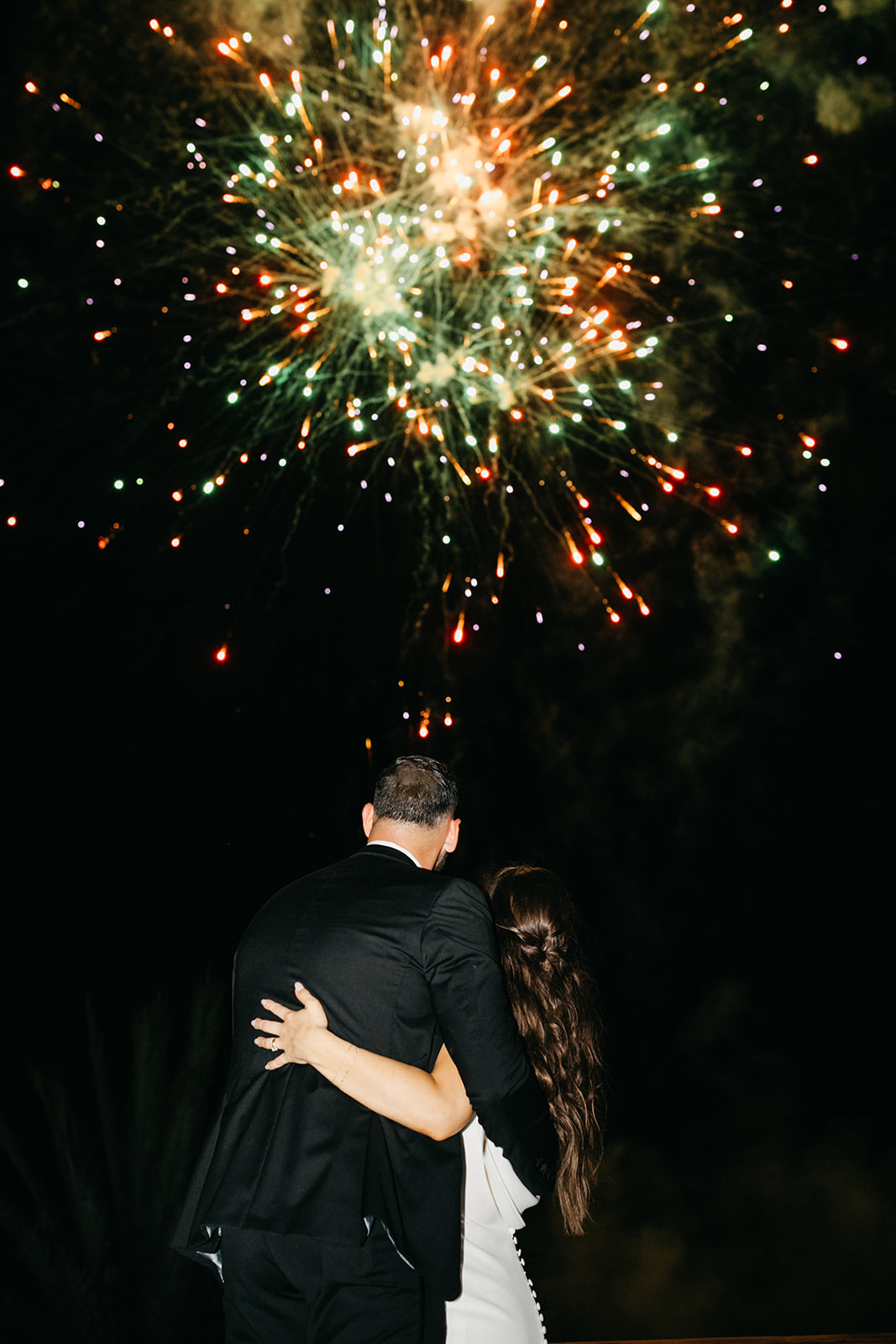Couple watches fireworks at elegant wedding in Cabo San Lucas at luxury resort.