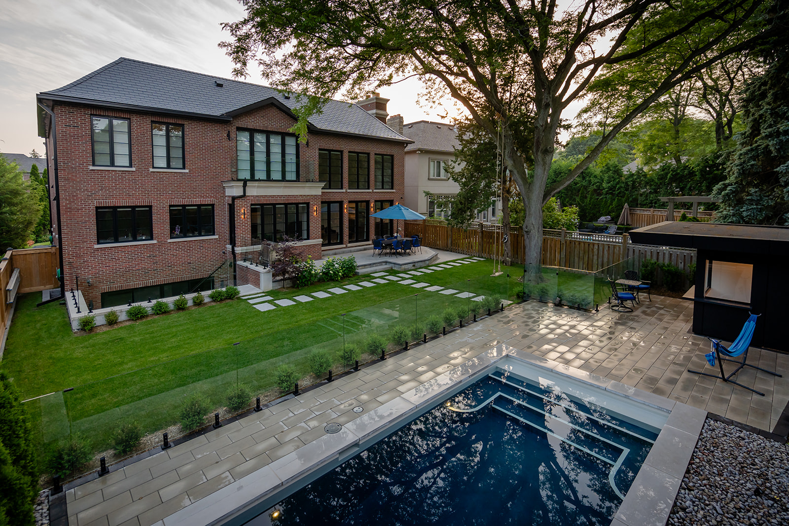 An inground pool surrounded by patio with grass backing onto the house.